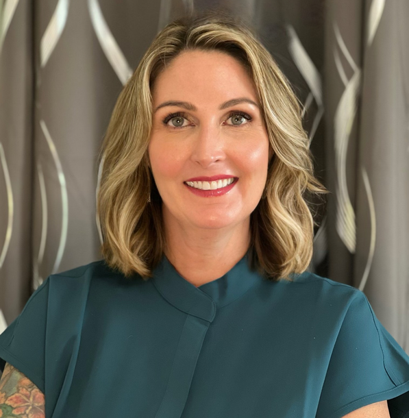 A woman in a blue shirt is smiling for the camera.