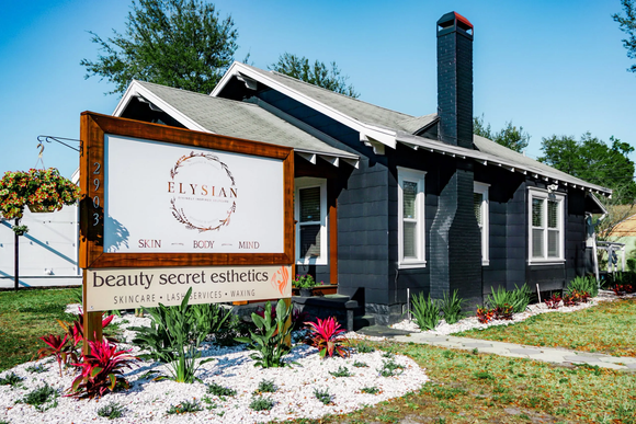 A black house with a sign in front of it that says beauty secret esthetics