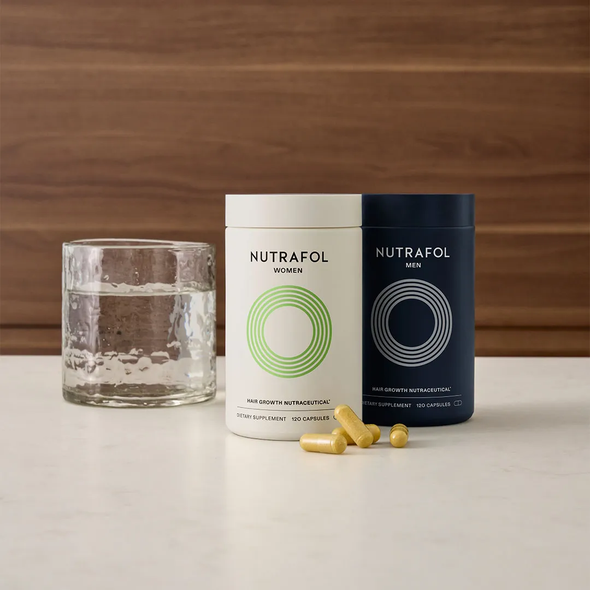 Two cans of nutrafol are sitting on a table next to a glass of water.