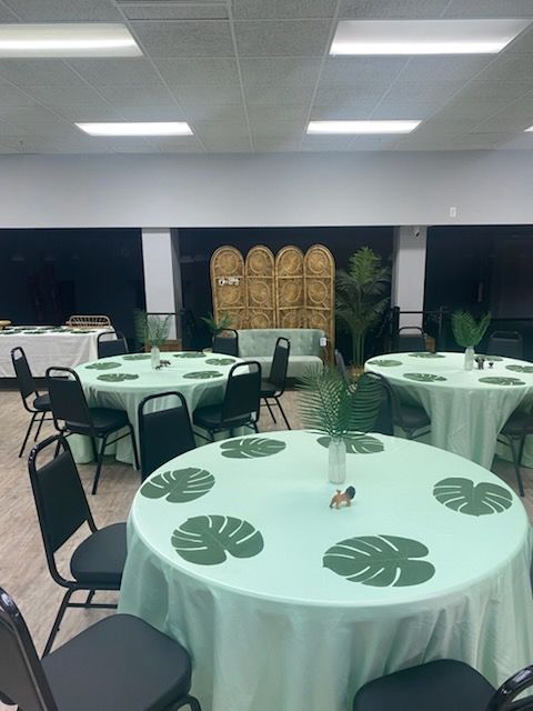A room filled with tables and chairs with green leaves on them.
