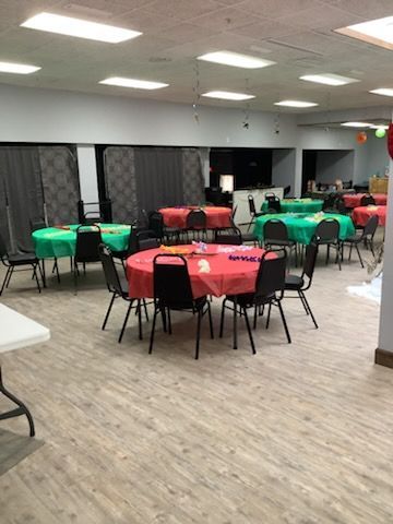 A large room with tables and chairs set up for a party.