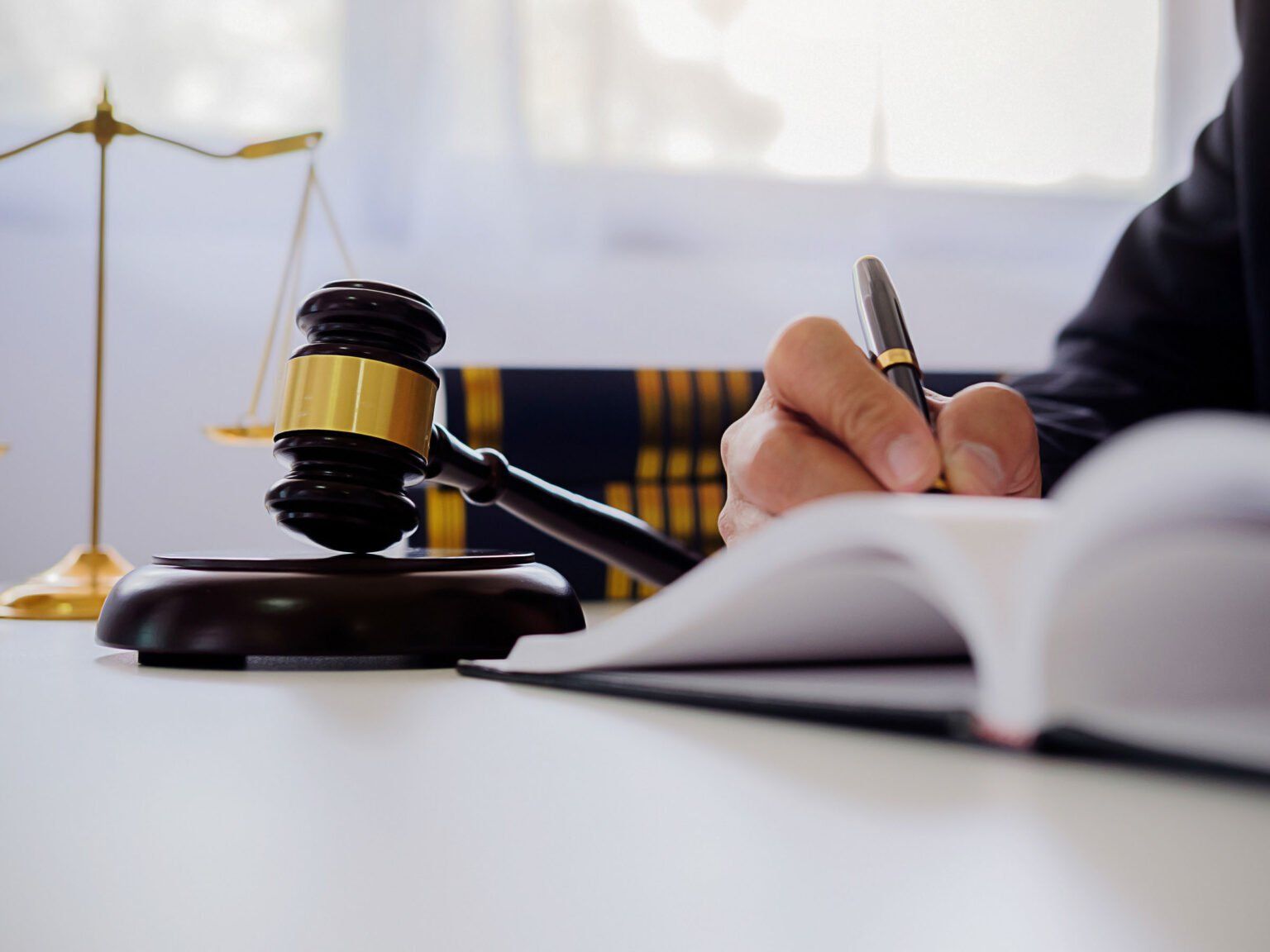 A person is writing in a notebook in front of a judge 's gavel.