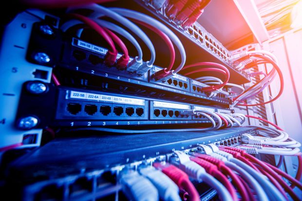 A server rack with many red and white Ethernet cables plugged into network patch panels and switches.