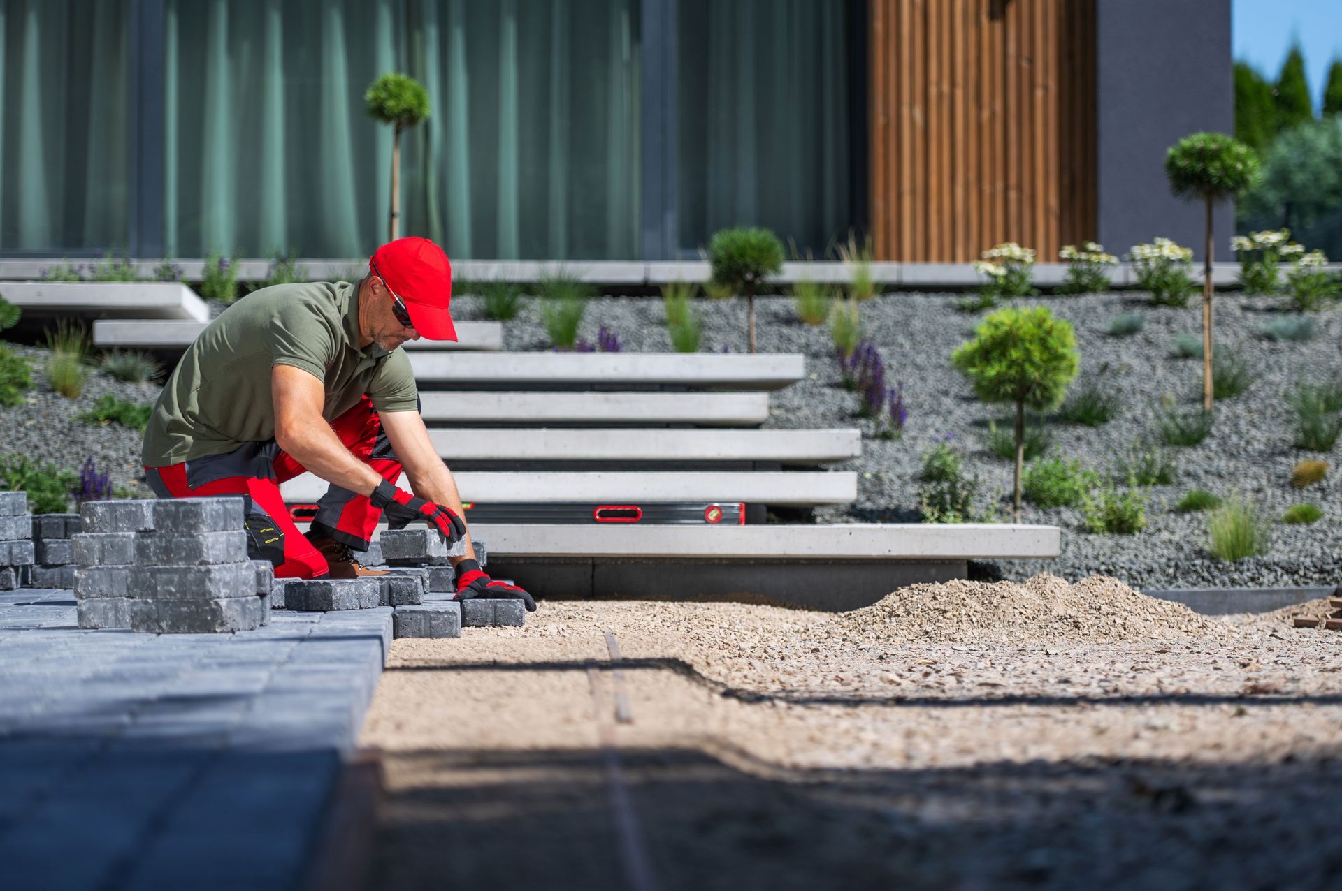 Worker installing paving stones while building a hardscape walkway.