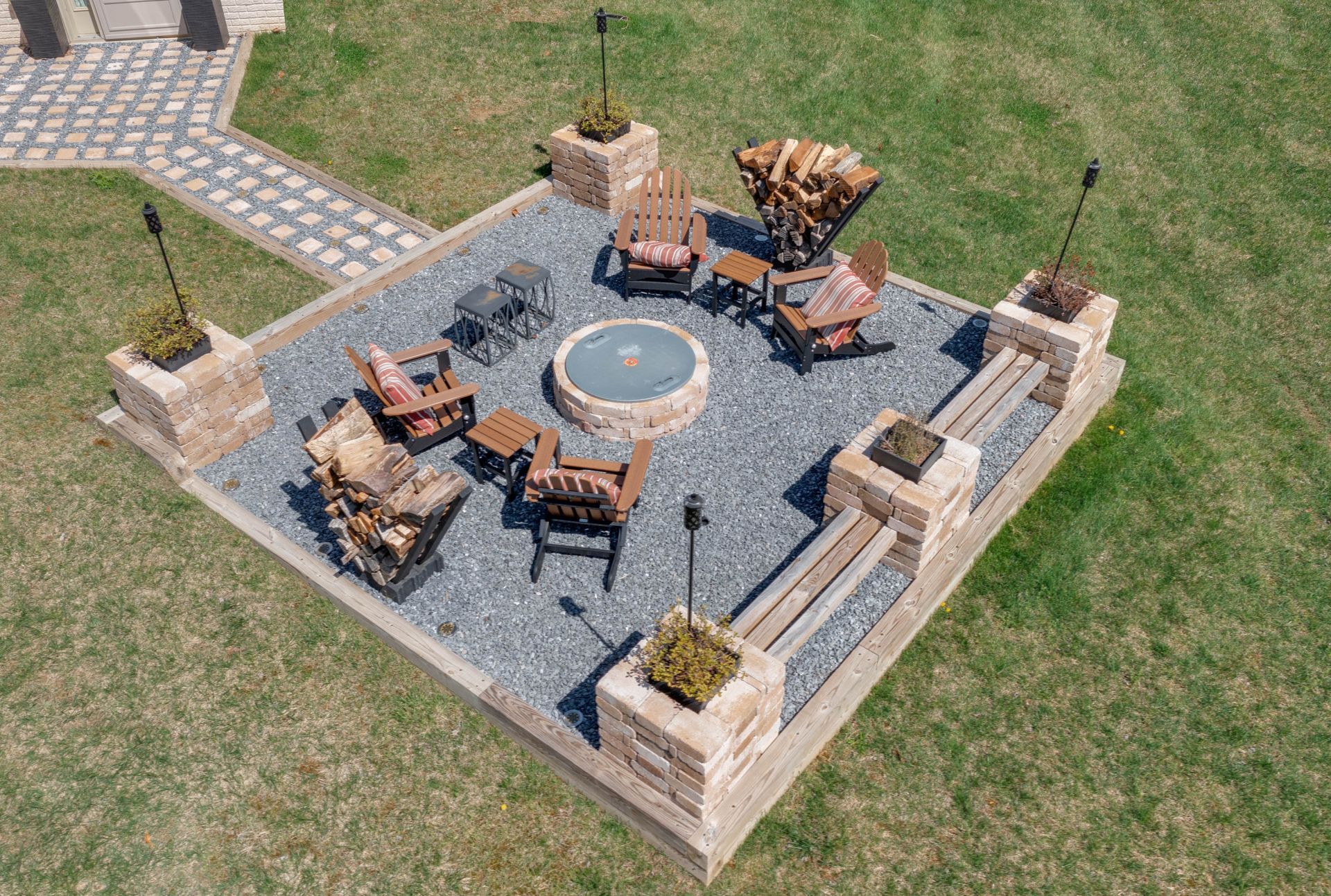 Outdoor hardscape fire pit area with stone seating and gravel flooring.