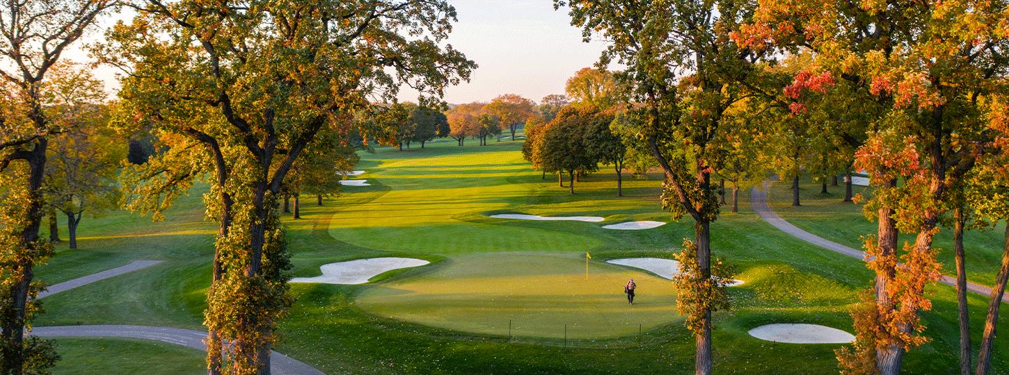 A luxurious stone house at dusk with a glowing pool and fire pit, surrounded by illuminated landscaping.
