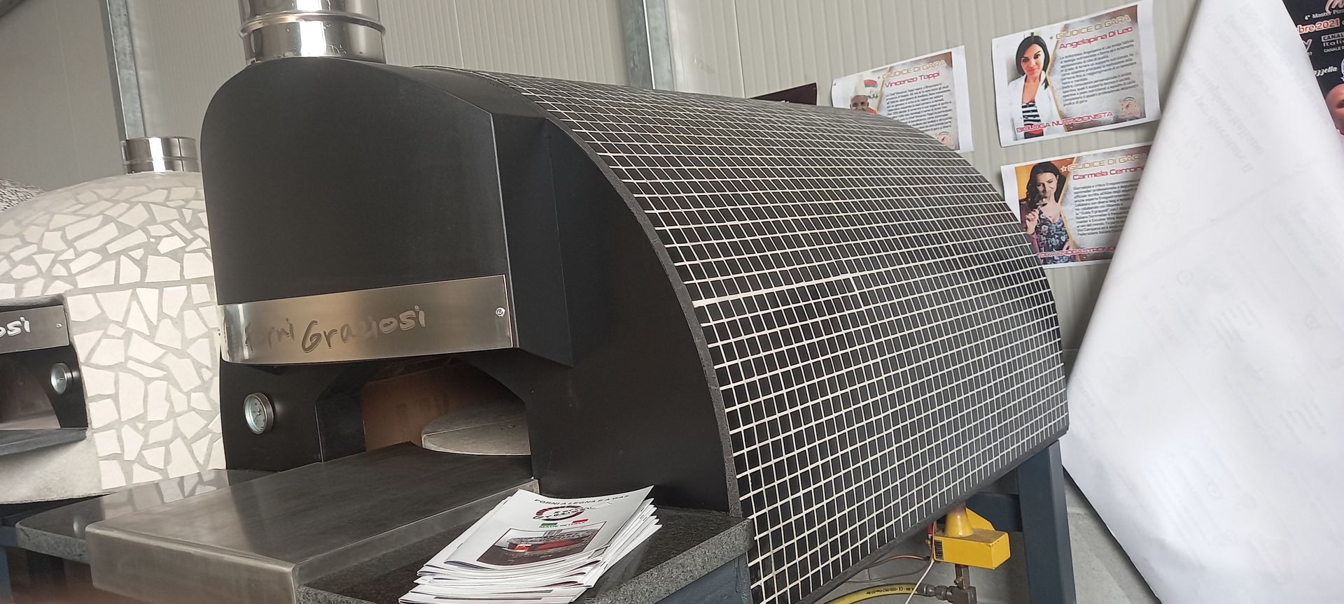 Un forno per pizza è appoggiato su un tavolo, accanto a un muro.