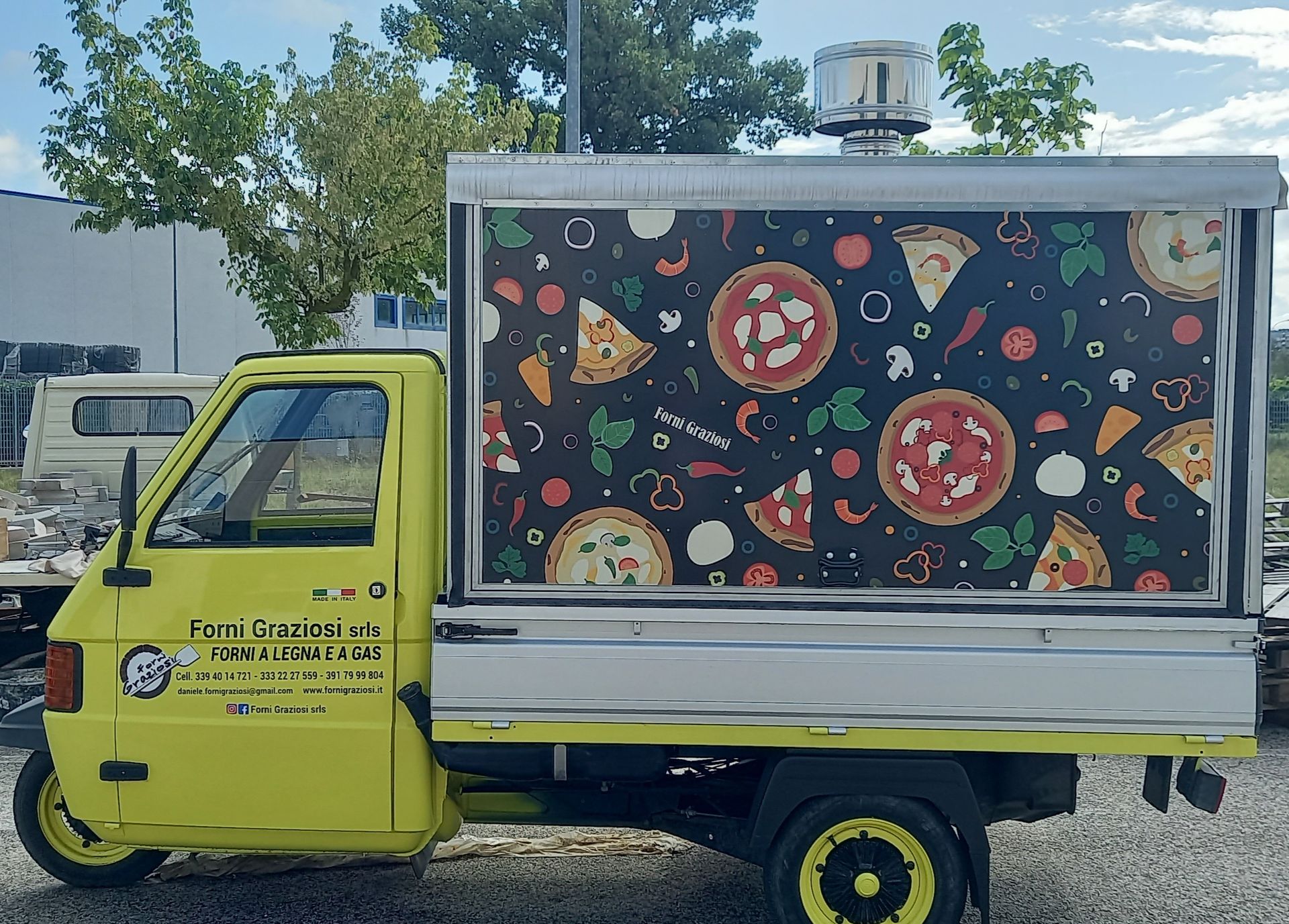 Un camioncino di cibo giallo con un disegno di pizza sul lato