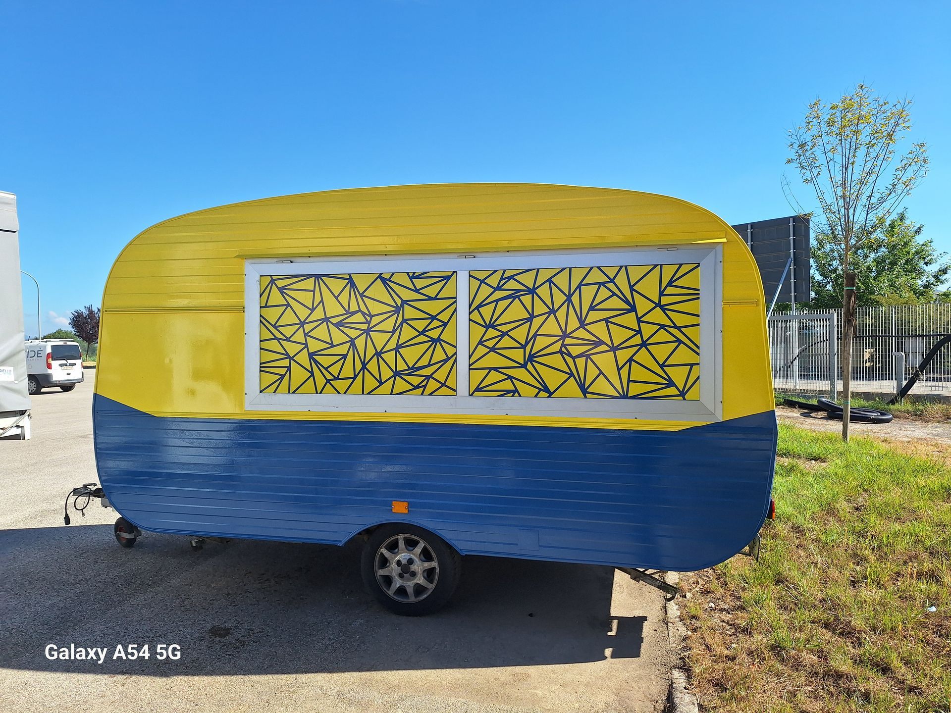 Un rimorchio giallo e blu è parcheggiato sul ciglio della strada.