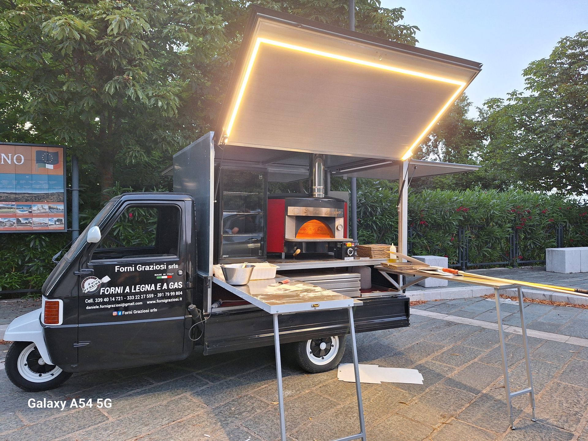 Un camioncino che vende cibo con un forno per pizza al suo interno è parcheggiato in un parcheggio.