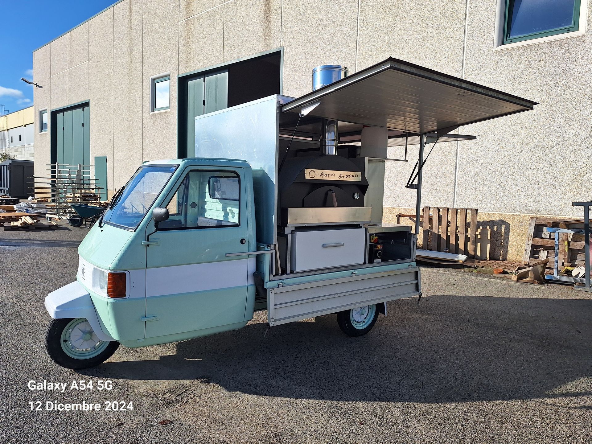 Un camioncino che vende cibo verde e bianco è parcheggiato davanti a un edificio.