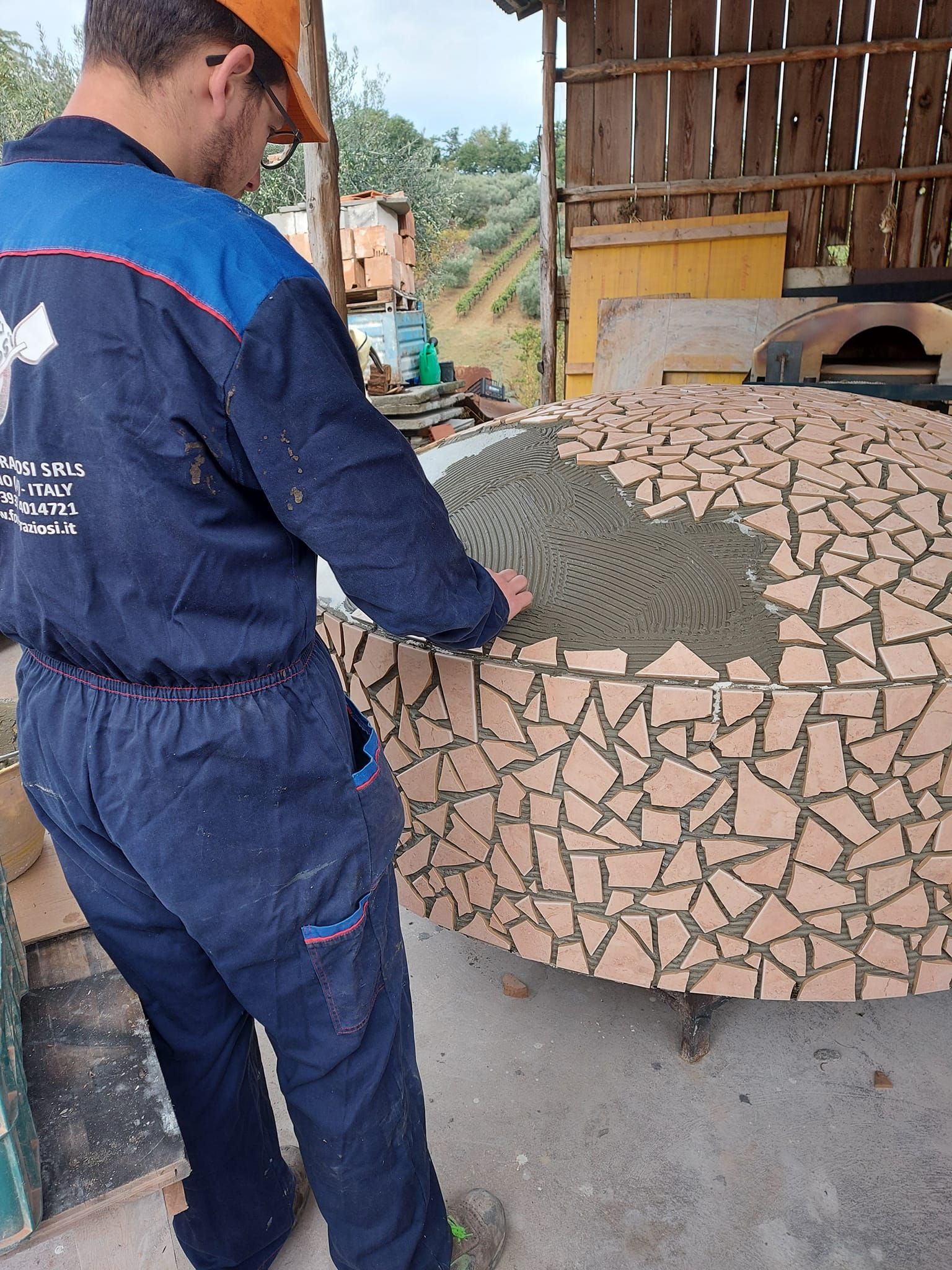 Un uomo con un casco è in piedi accanto a un muro di mattoni.