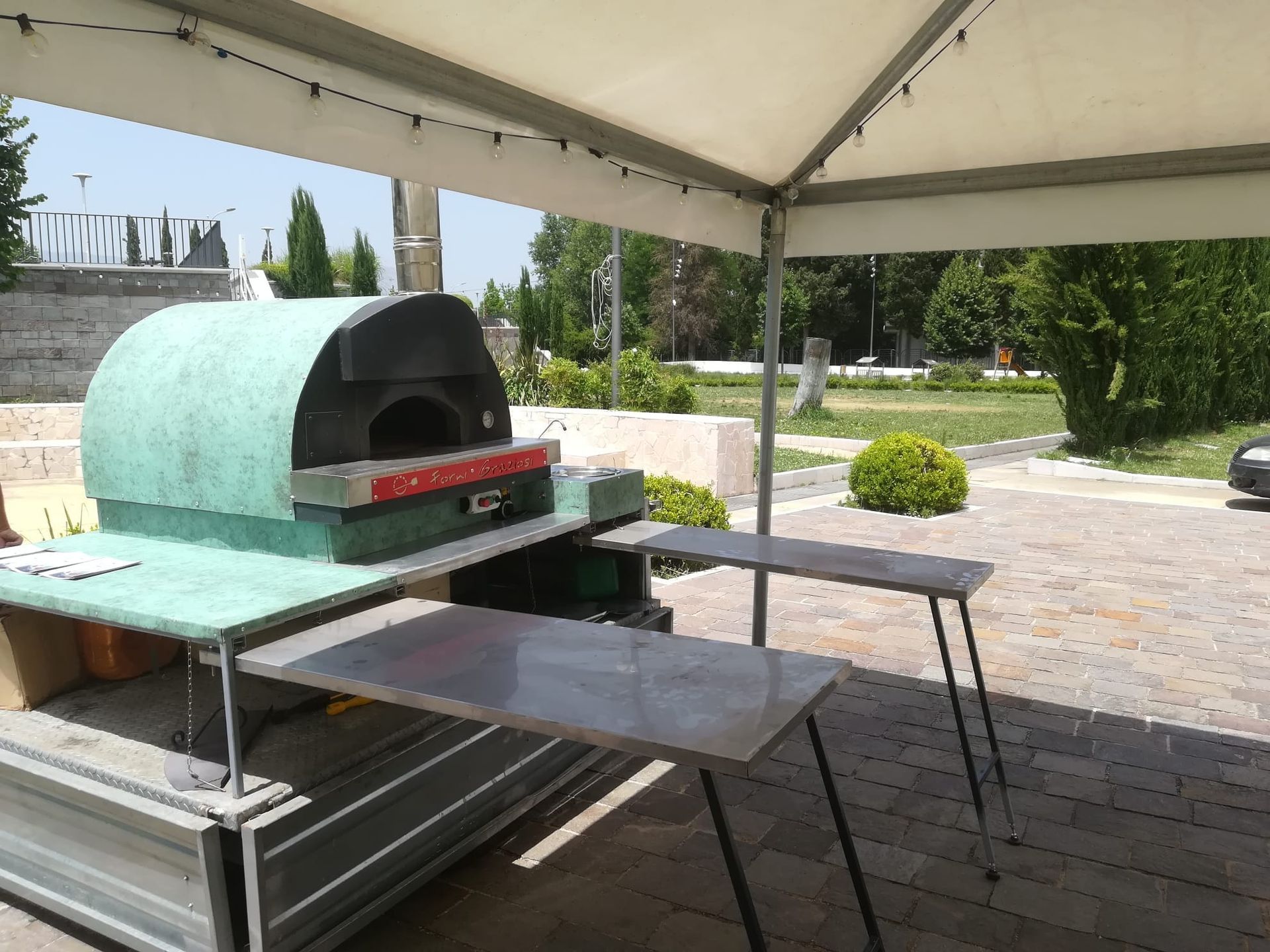 Un forno per pizza è posizionato sopra un tavolo sotto una tenda.