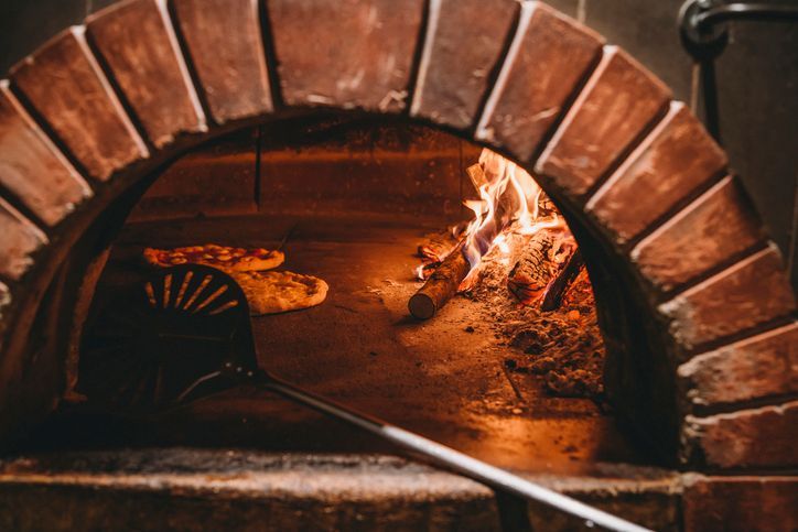 Una pizza viene cotta in un forno a legna.