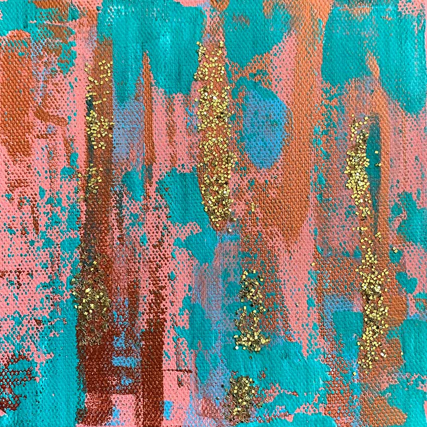 A close up of a painting with pink and blue paint and gold glitter.