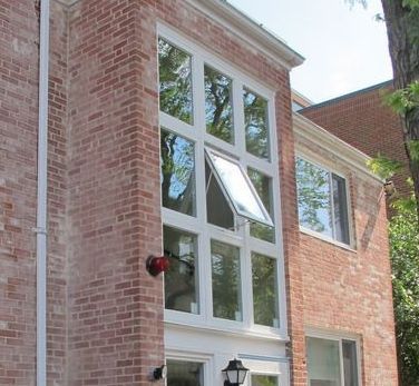 A brick building with white windows and a red light on the side