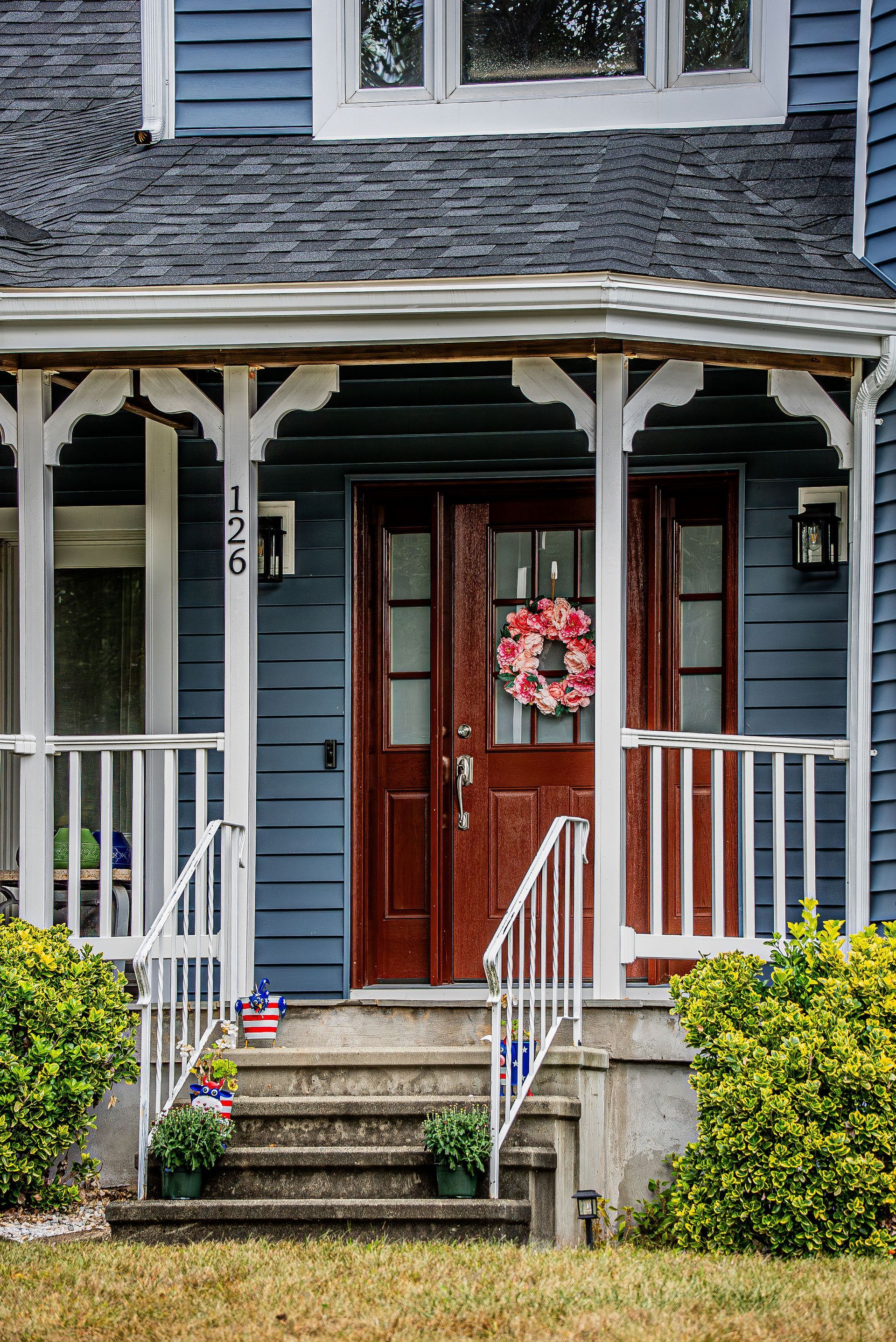 Blue house with dark red door, white porch trim, steps, and wreath. Number 175 on the side.