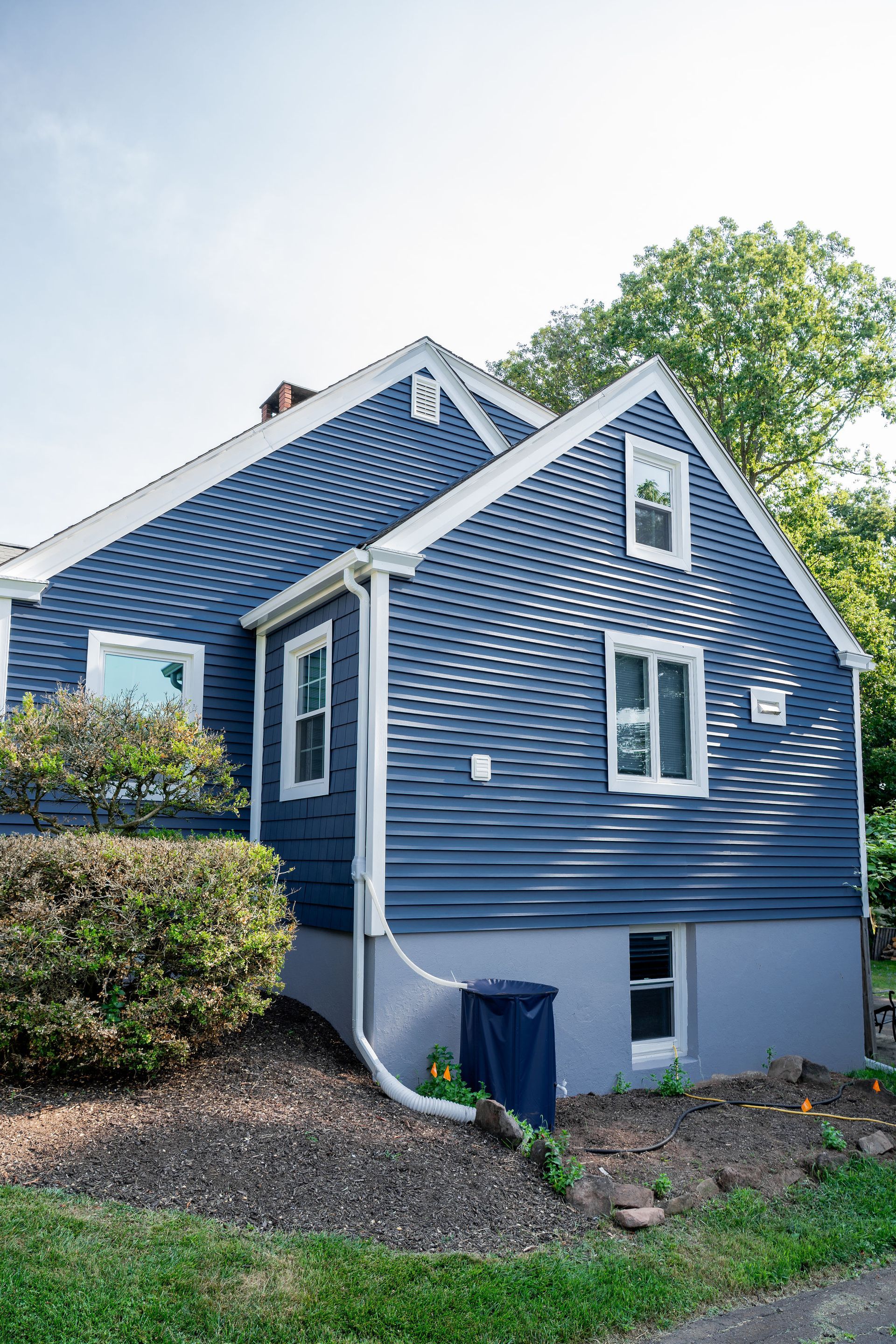Blue house with white trim, windows, and landscaping.
