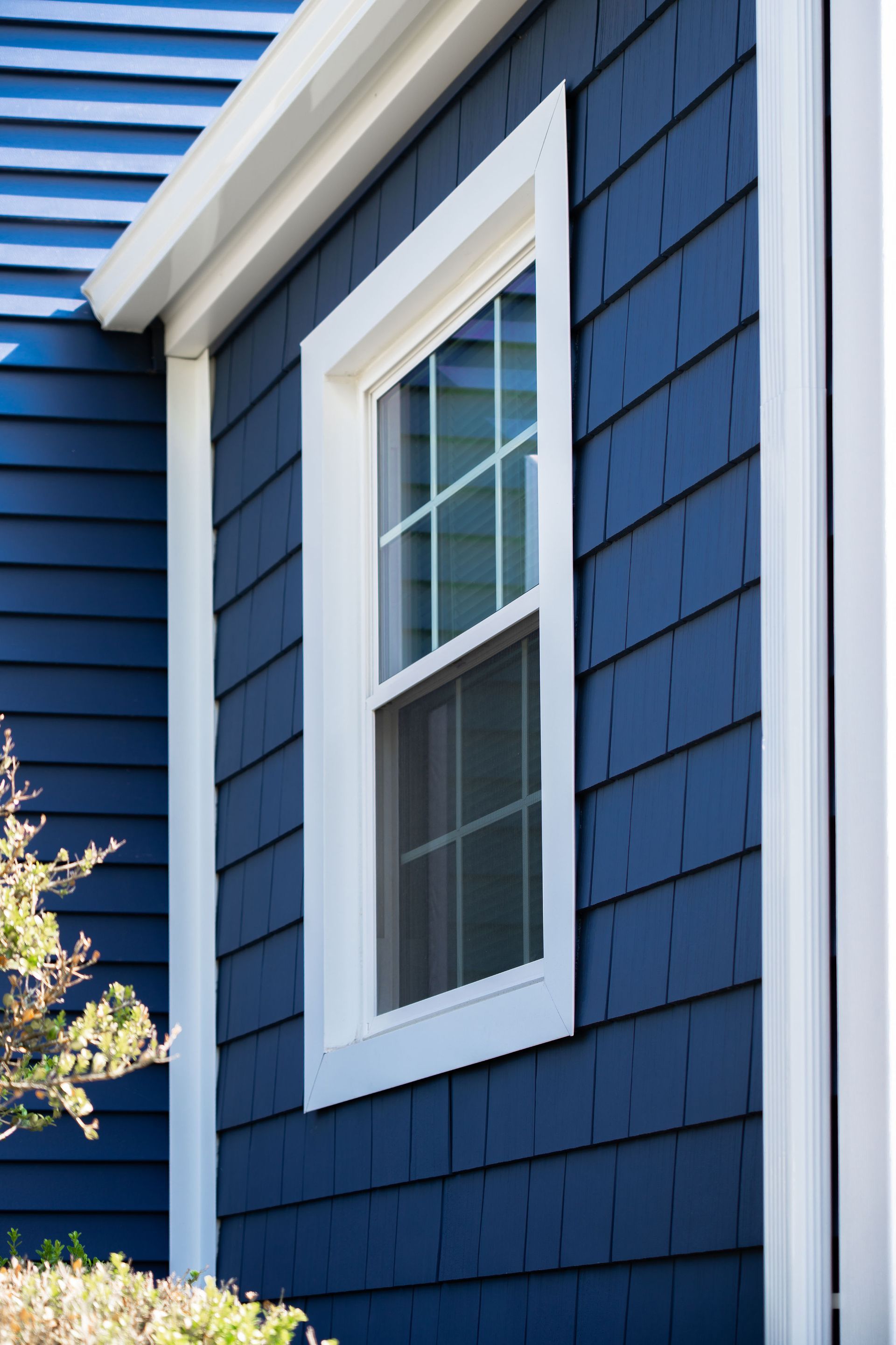 Blue shingle siding with a white-framed window.