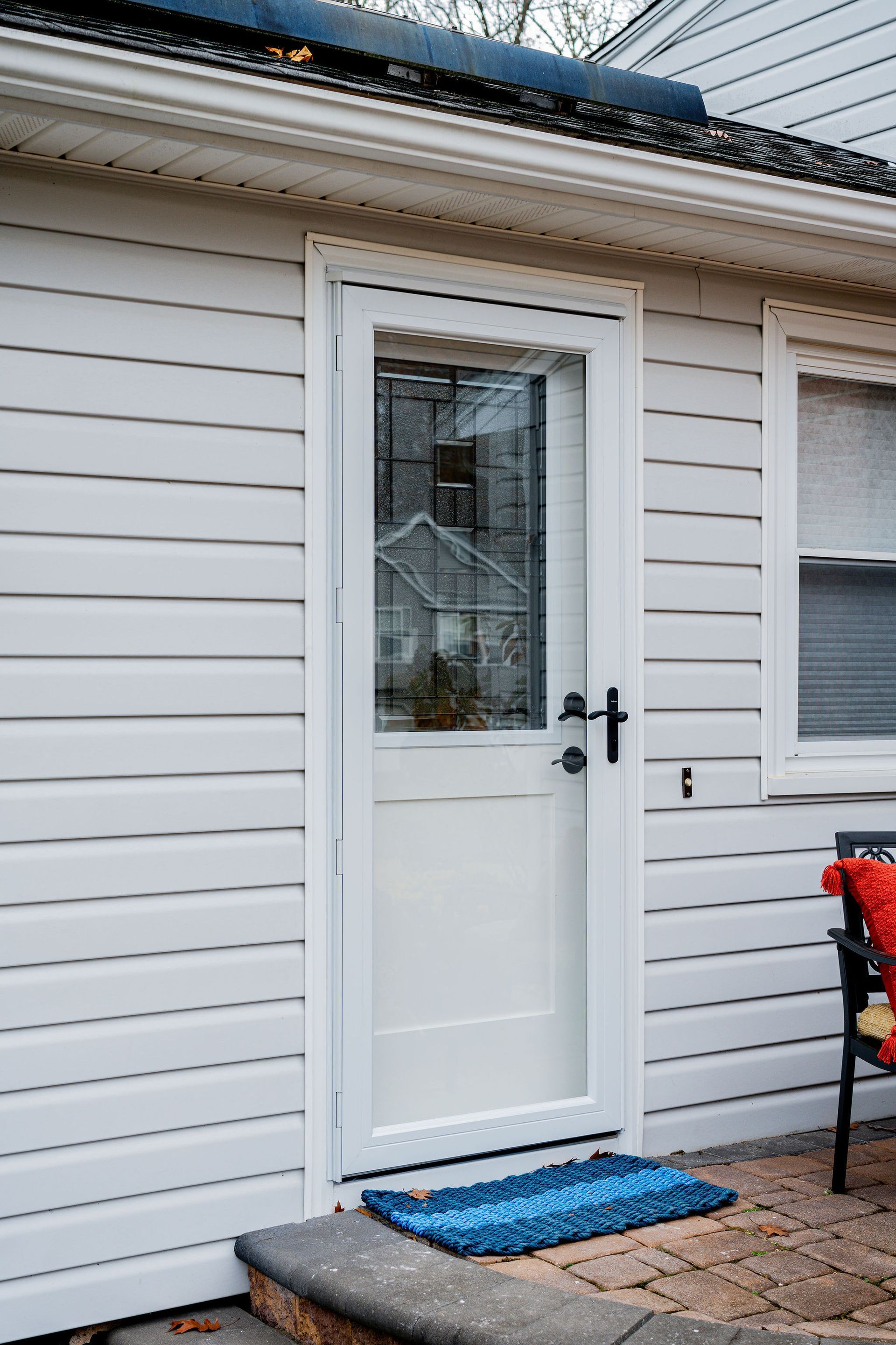 White door with glass panel, blue welcome mat on a porch.