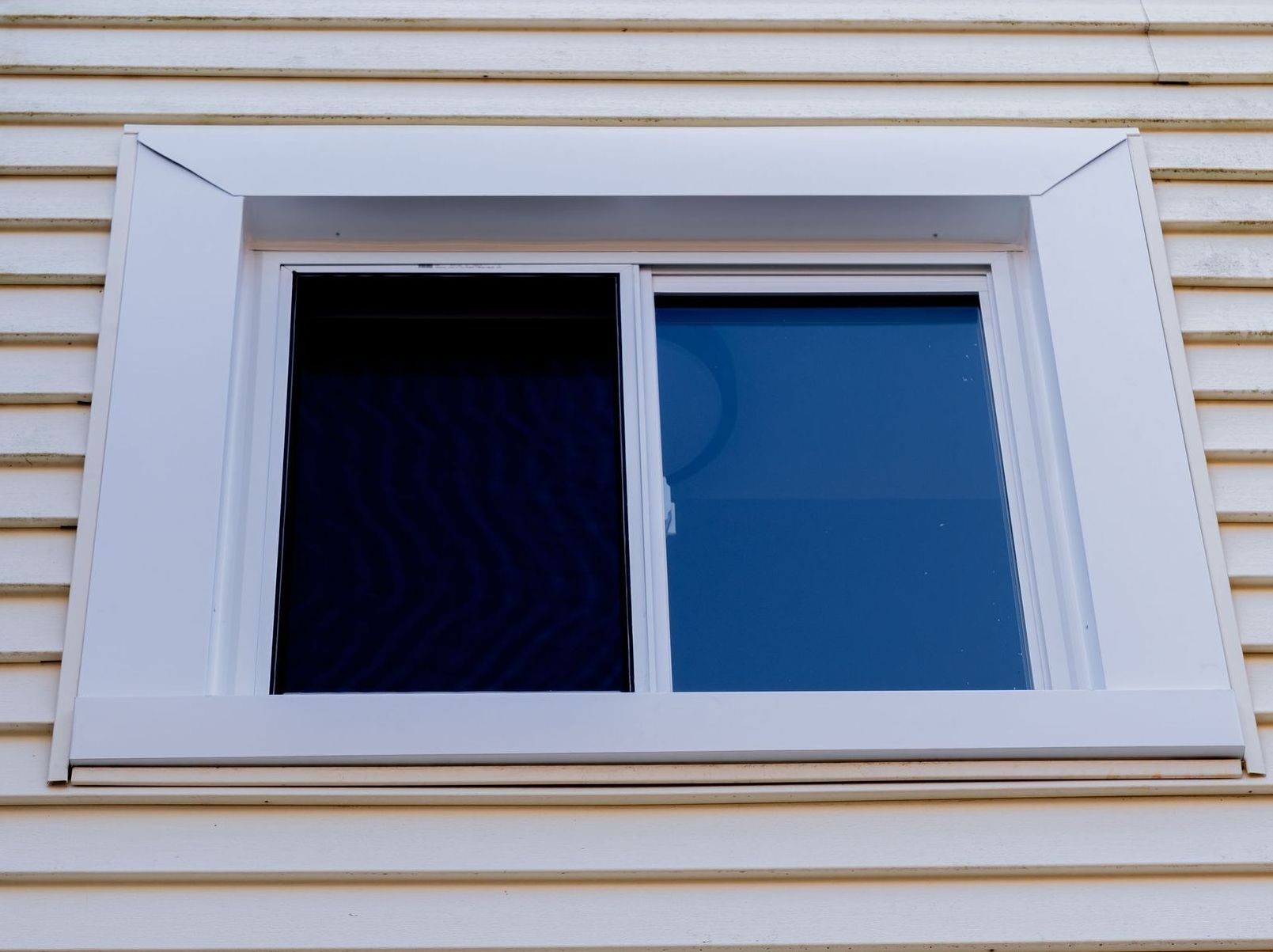 A rolling window on the side of a house with a blue glass