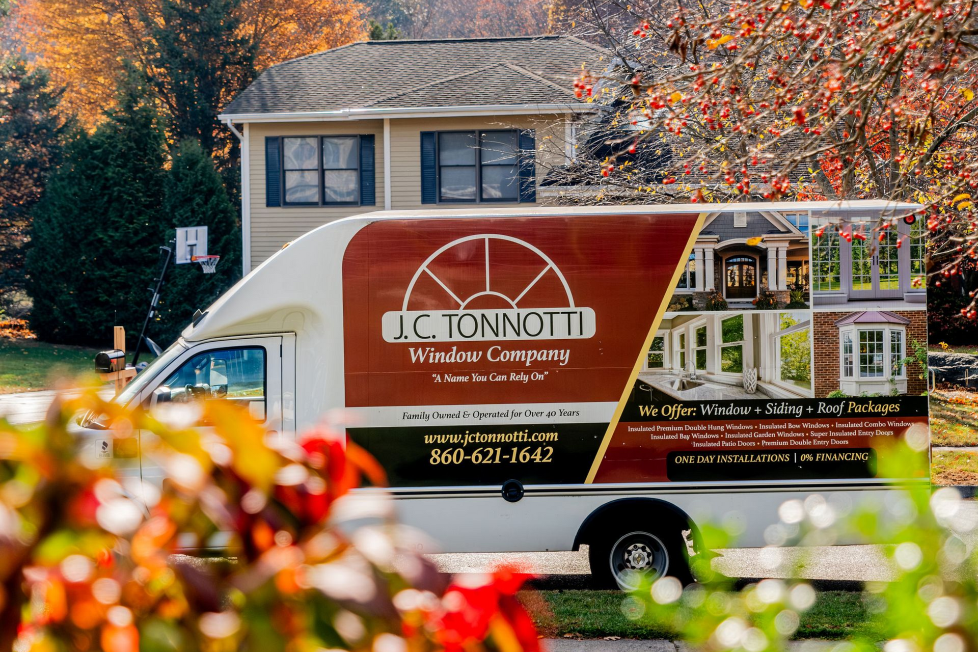 J.C. Tonnotti Window Company van parked in front of a house, with autumn foliage.