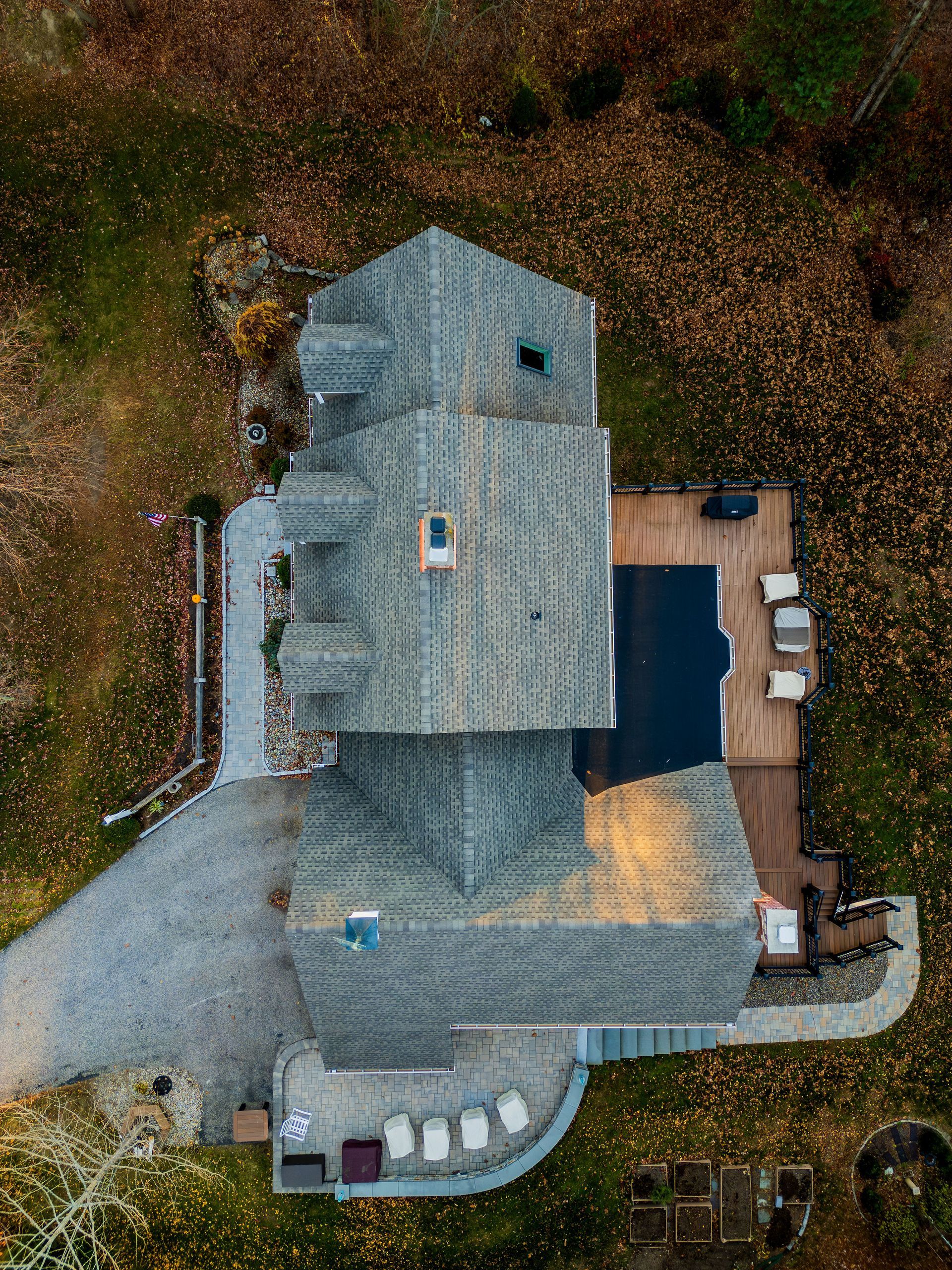 Overhead view of a house with a pool and patio surrounded by autumn foliage.