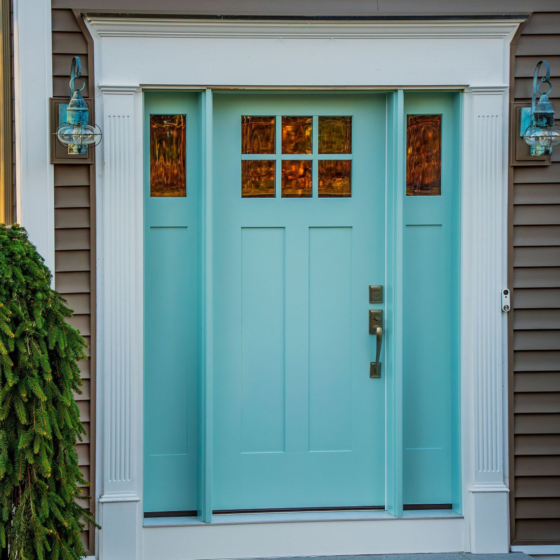 A light blue front door is on a brown house.