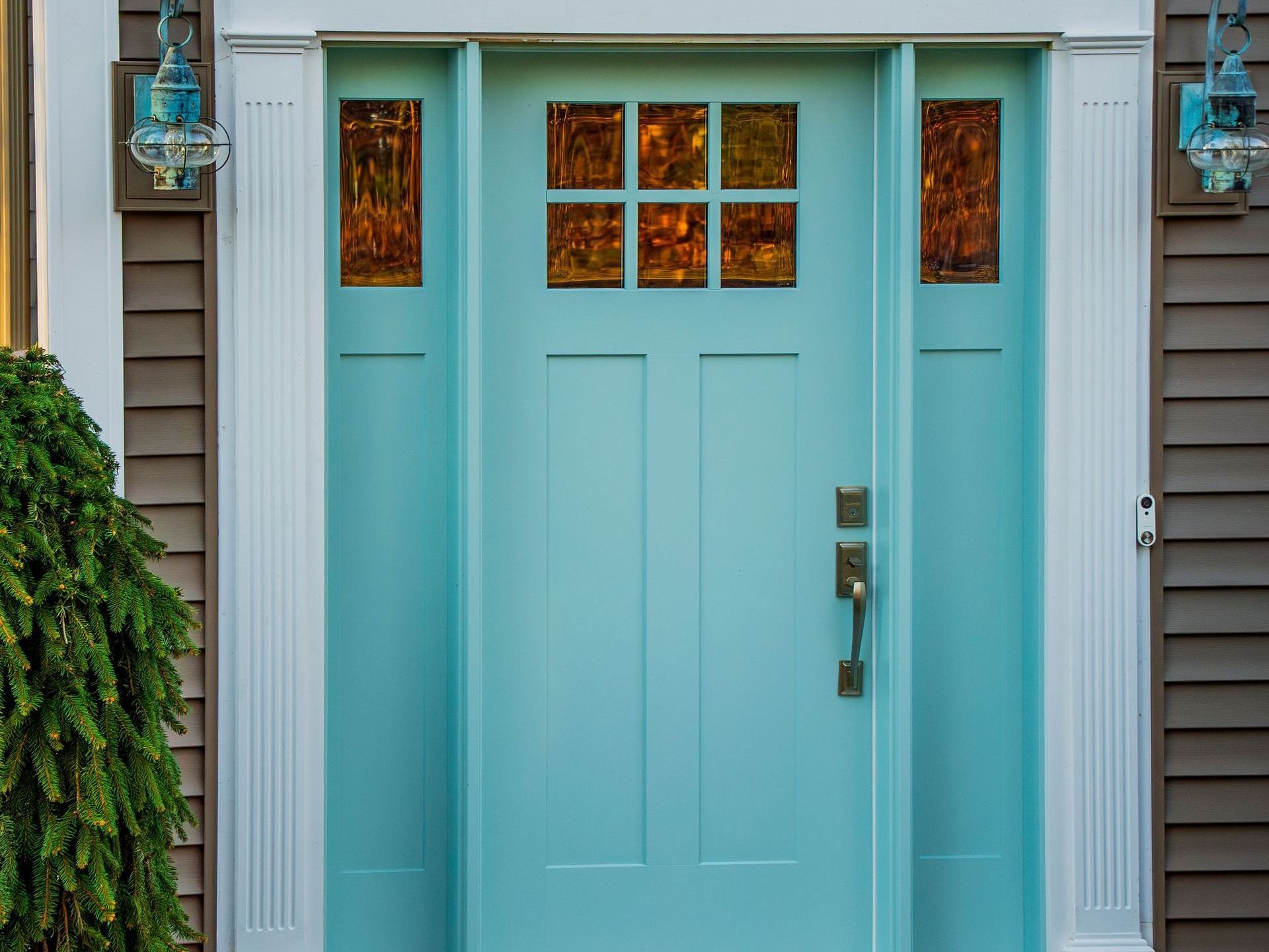 A light blue front door with stained glass windows on a house.