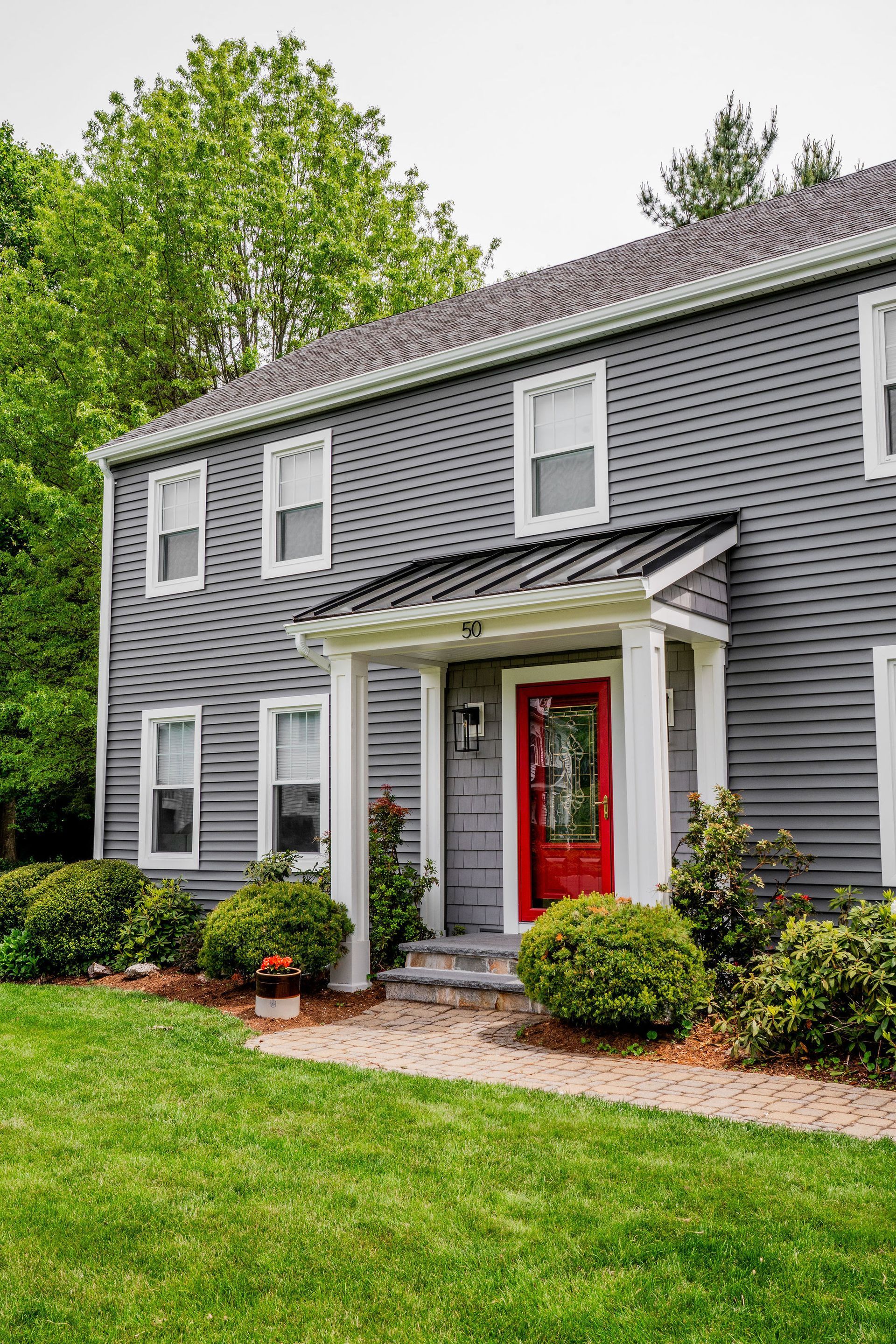 Gray two-story house with red door, white trim, and green lawn.