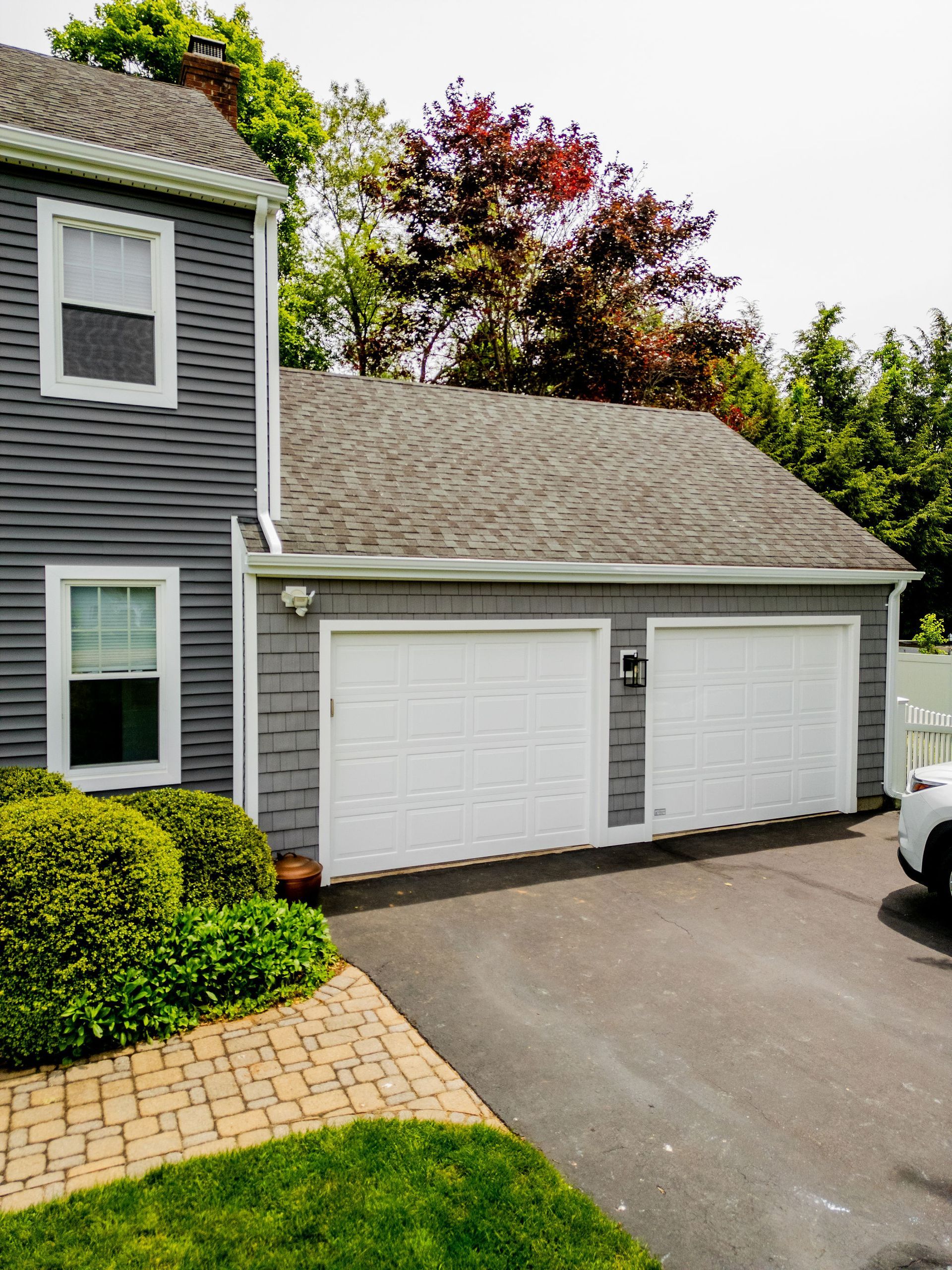Gray house with white garage doors and asphalt driveway.