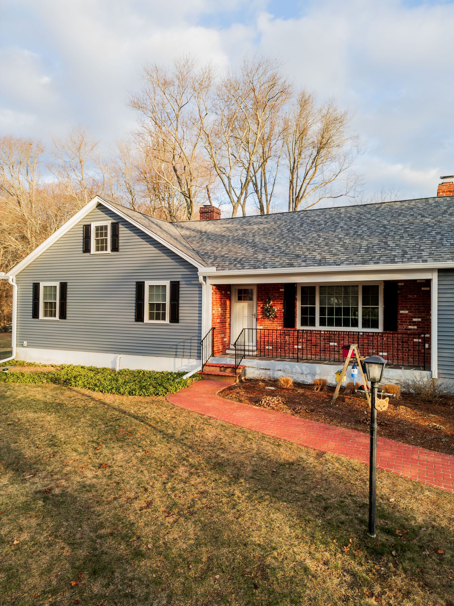 Ranch-style house with blue siding, brick accents, and a red walkway leading to the front door.
