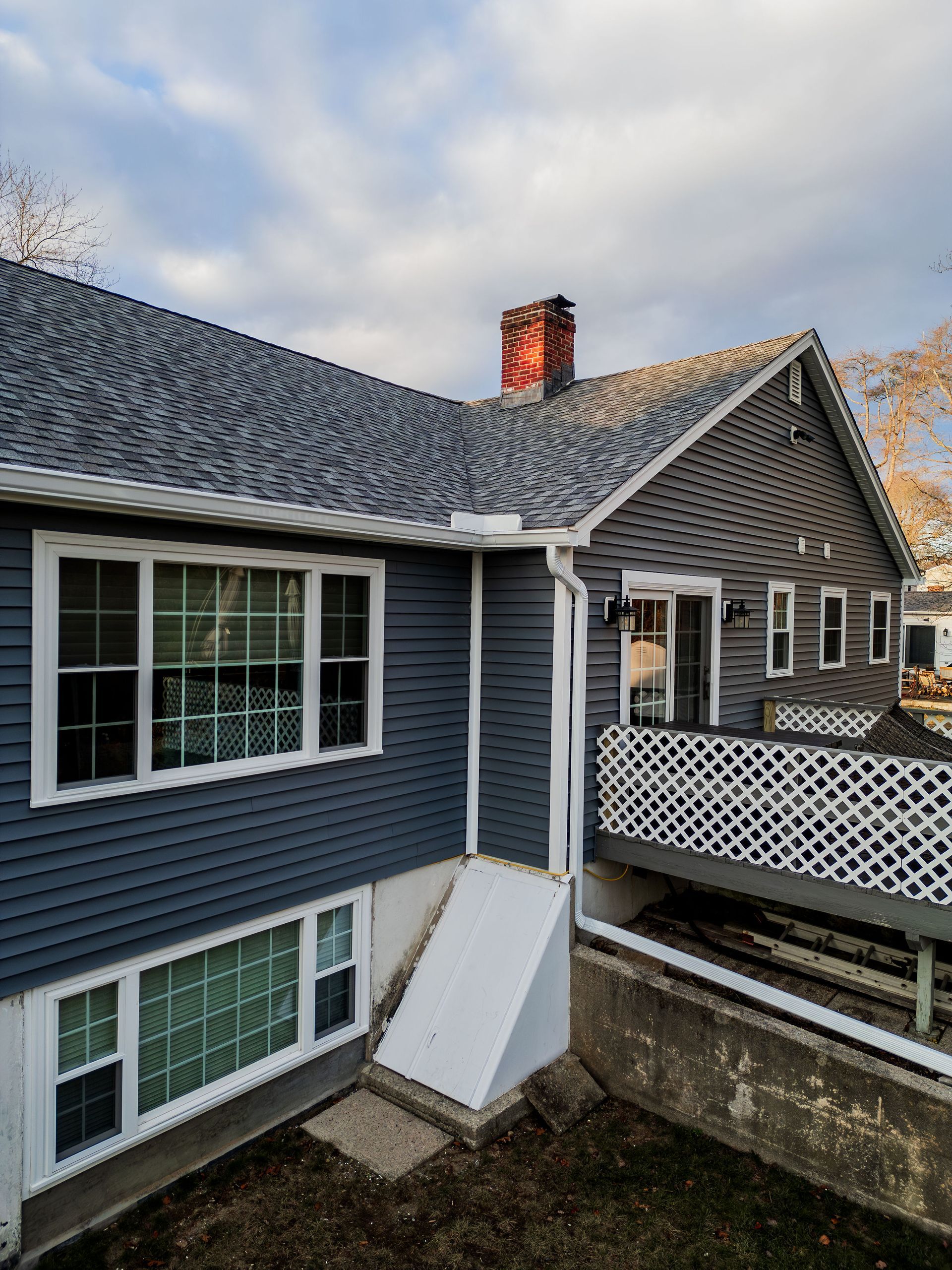 Dark blue house with a white hatch door, windows, and a deck. Overcast sky.