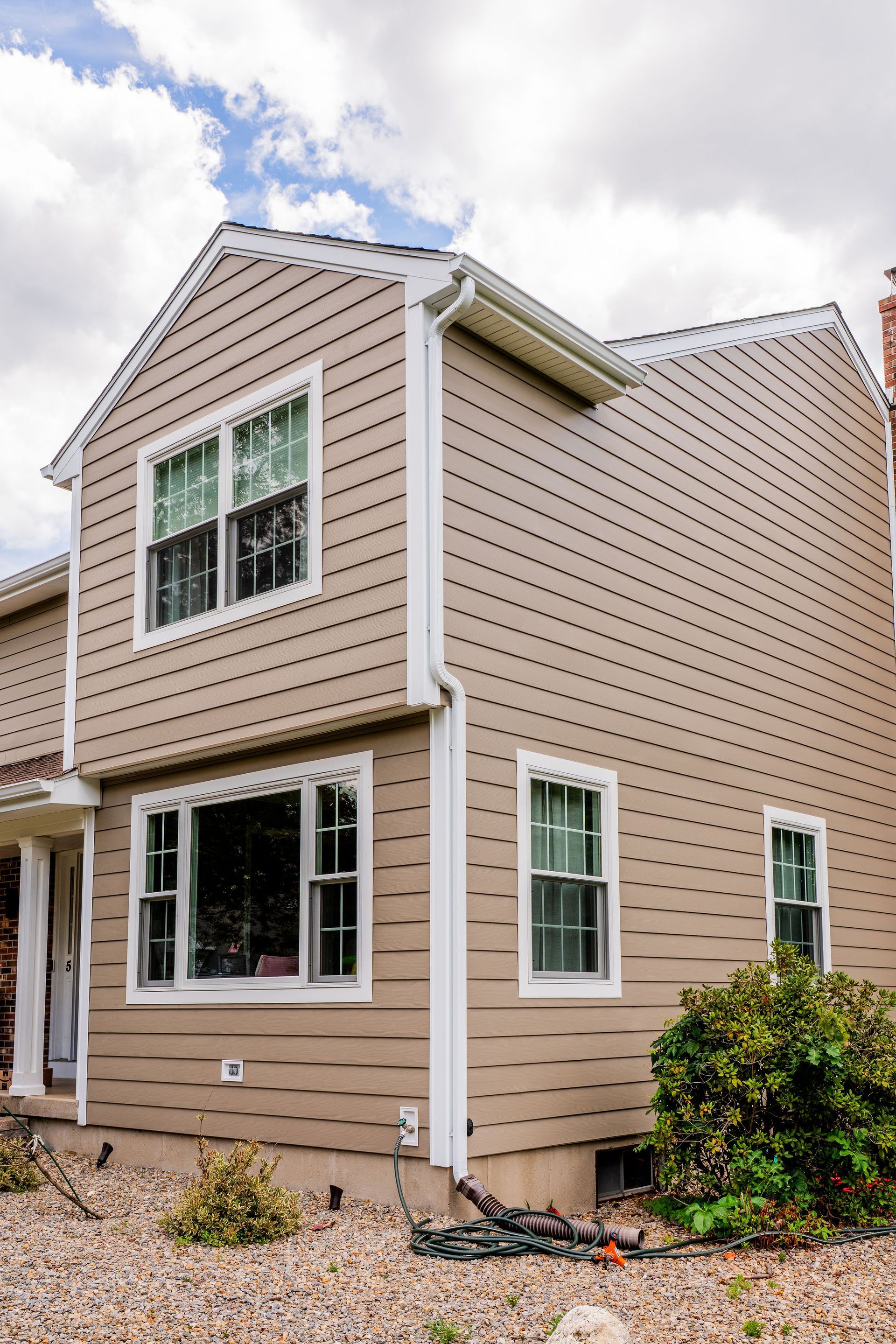 Beige two-story house with white trim, windows, and siding.