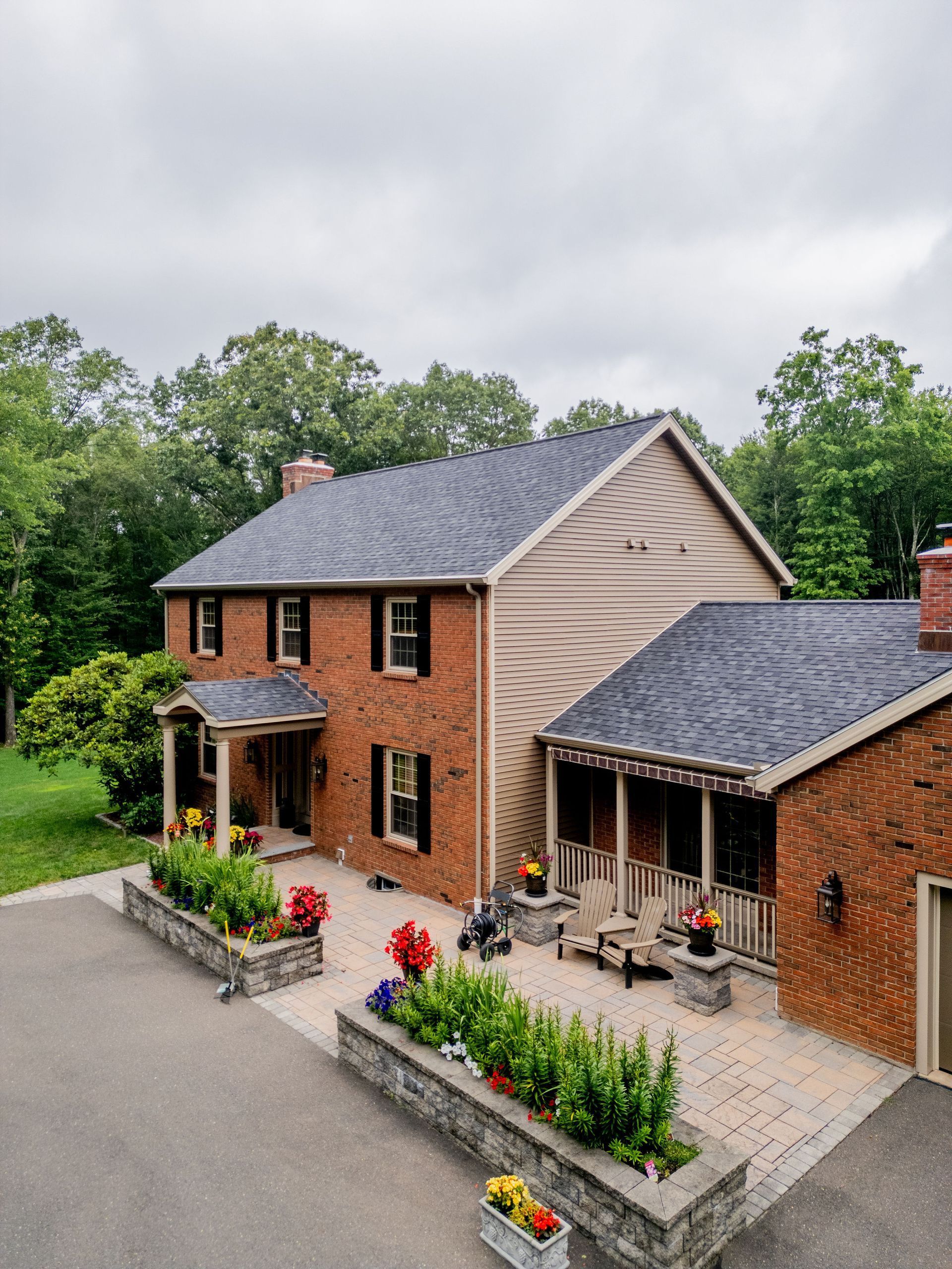 Brick house with a patio and flower boxes, under a cloudy sky.
