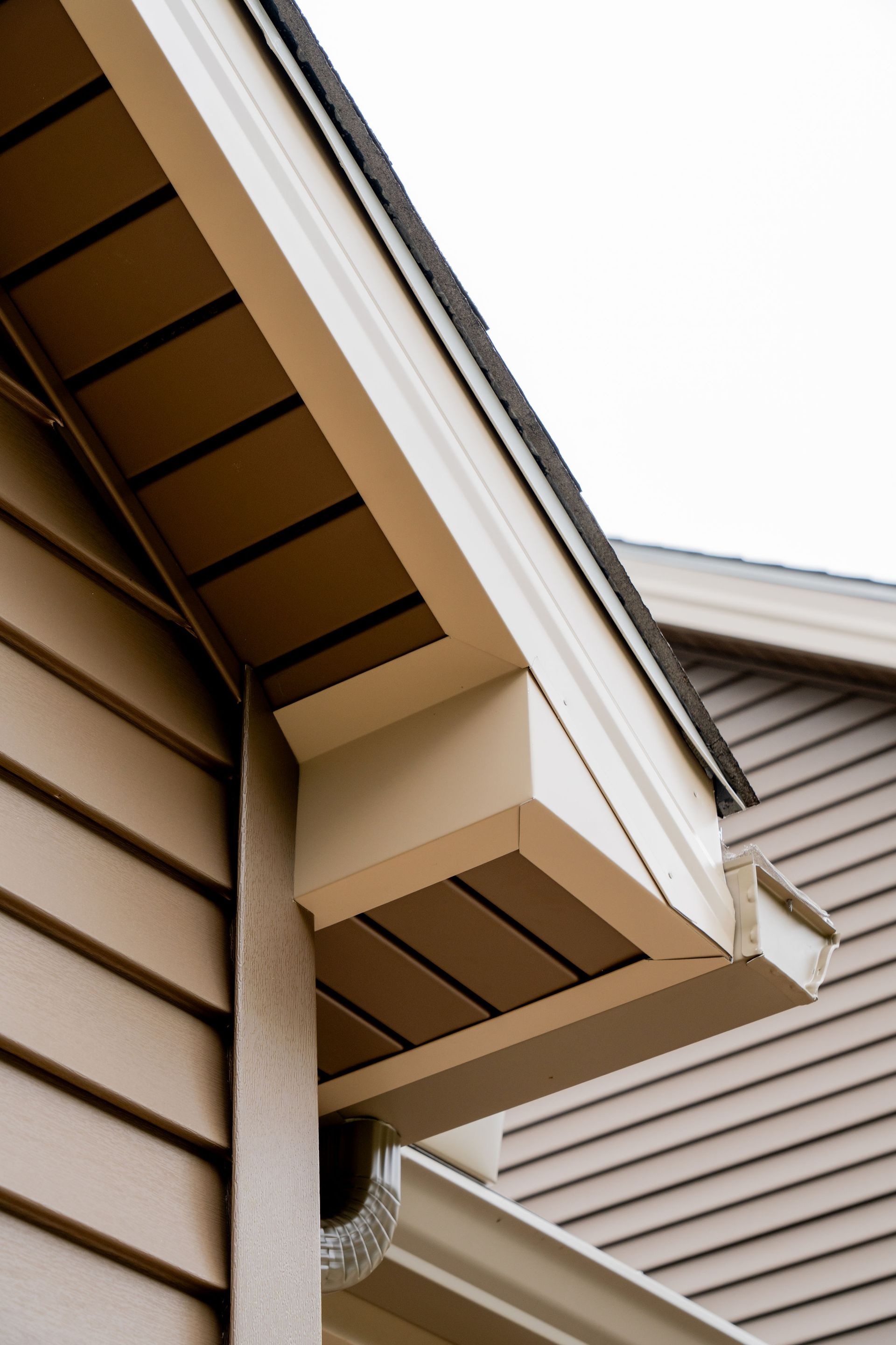 Tan house exterior with brown trim, soffit, and gutters.