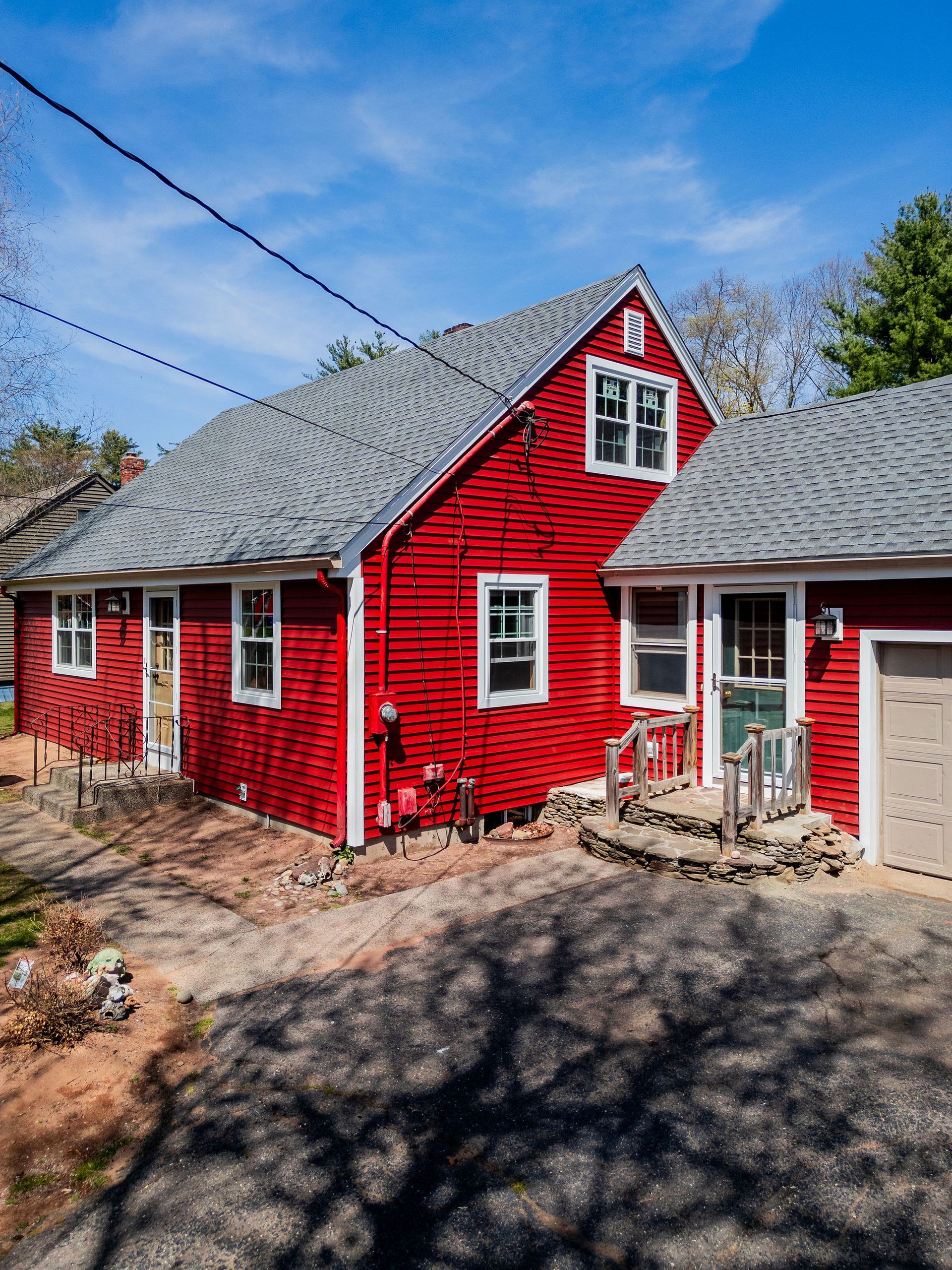 Red house with white trim, gray roof, and attached garage on a sunny day.