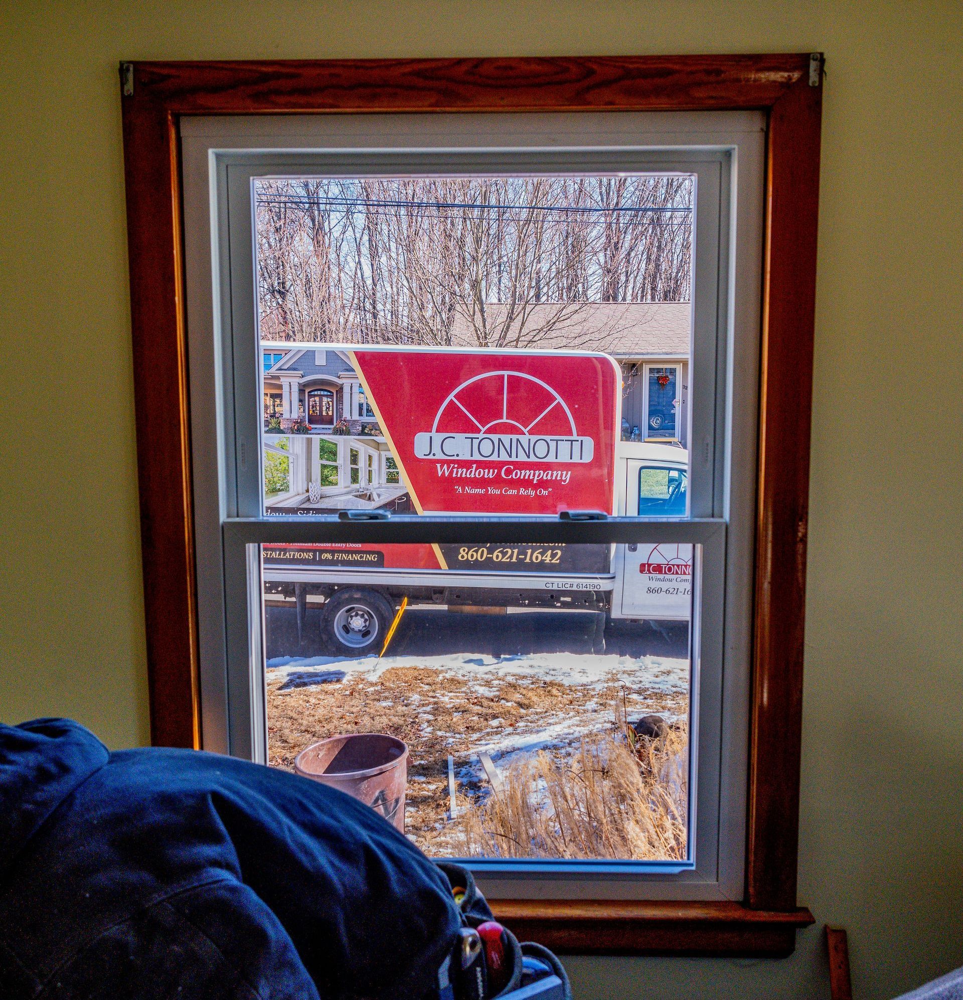 A double hung window with a jc tonnotti box truck outside