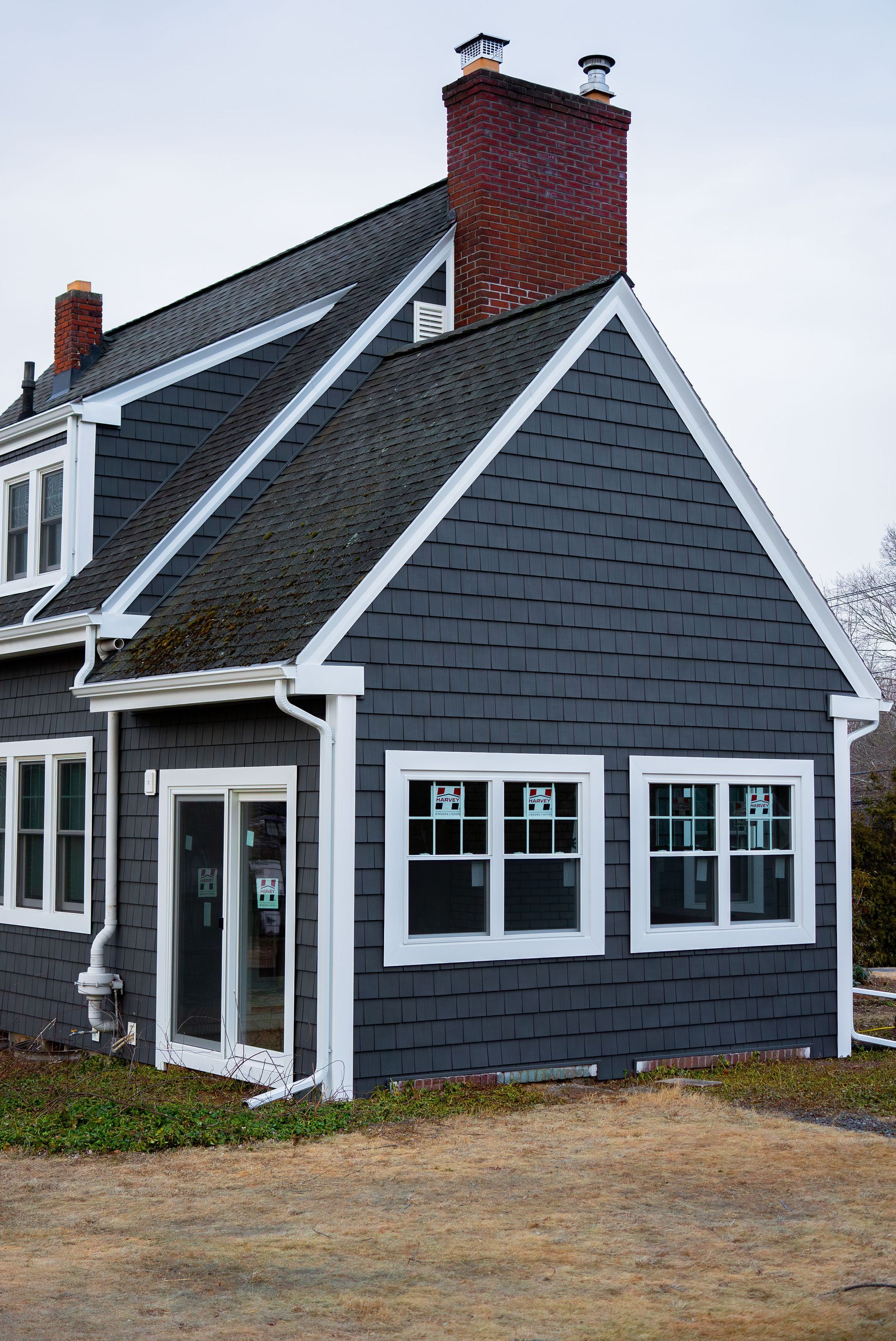 Gray house with white trim, windows, and a red brick chimney.