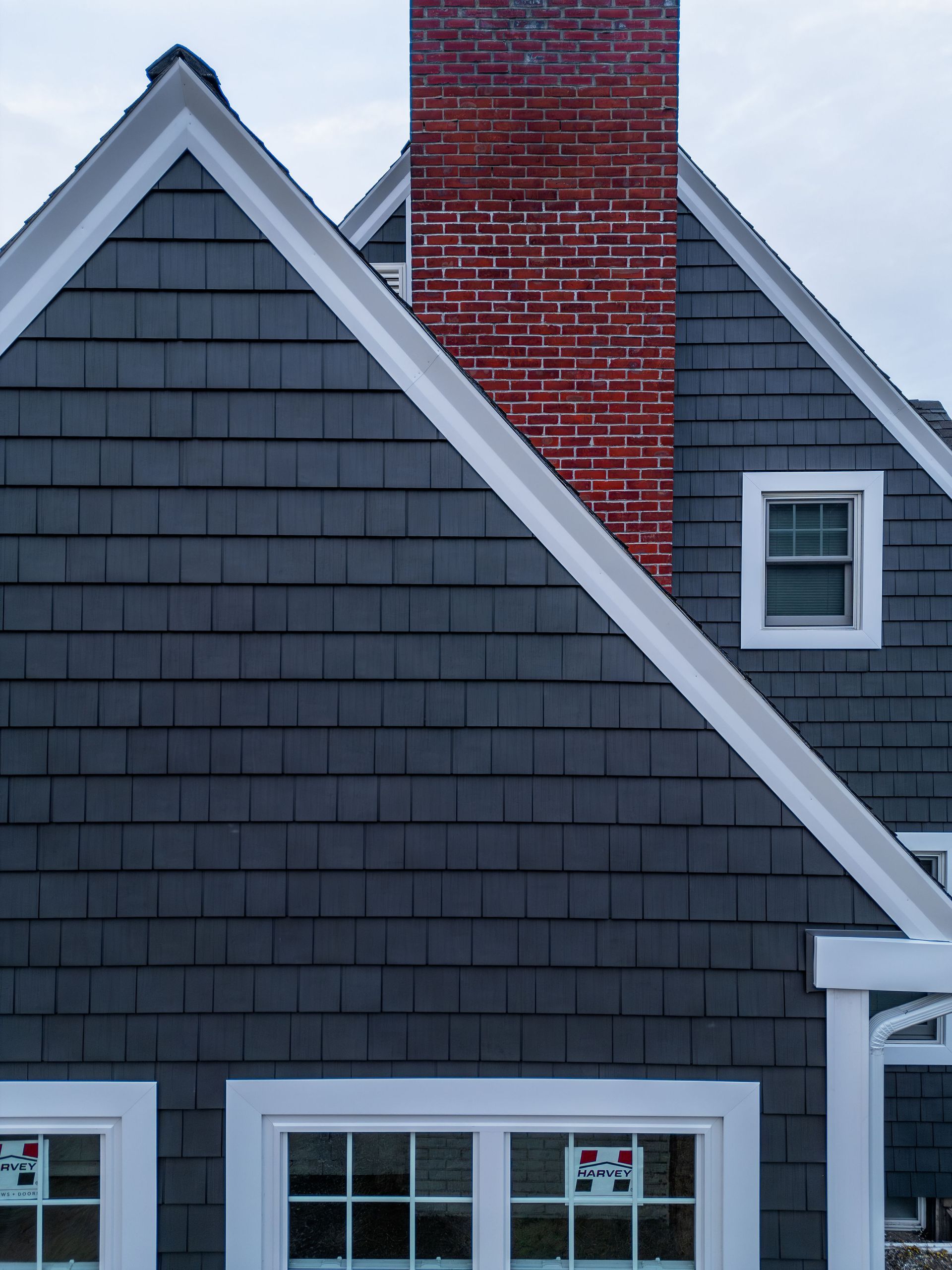 Gray shingled house with white trim, brick chimney, and windows.
