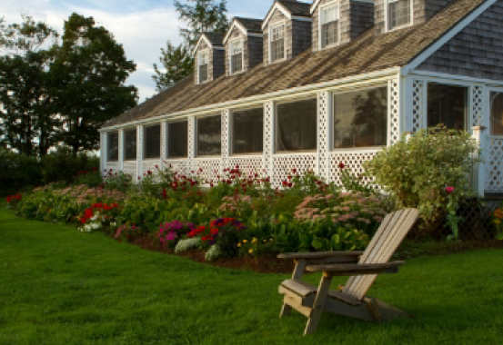 A house with a screened in porch and a chair in front of it