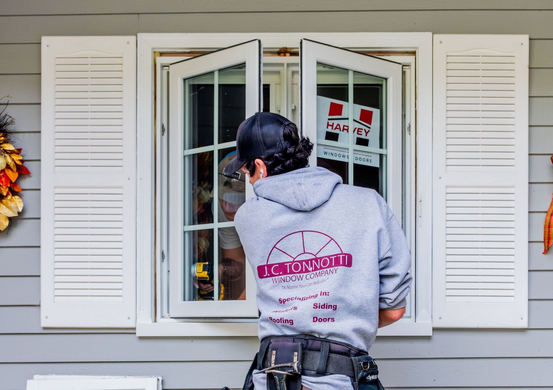 A man is installing a casement window on a house.