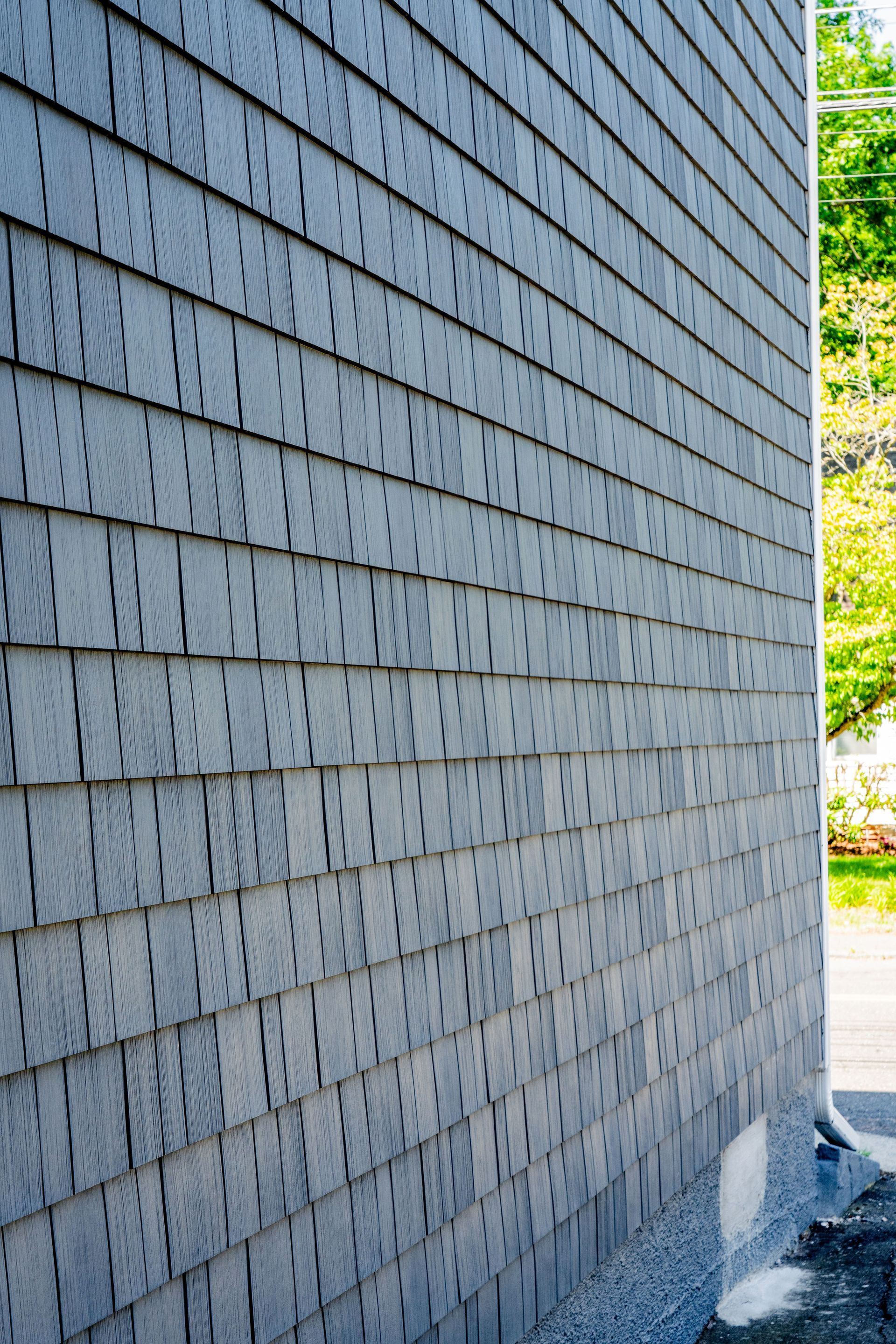 Gray wooden shingles covering the exterior wall of a building.