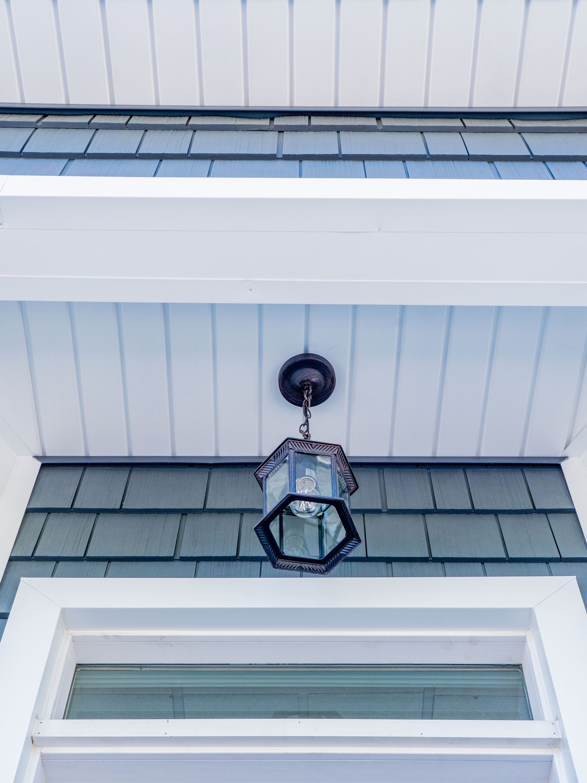 Exterior view with hanging lantern, blue siding, white trim, and a window.
