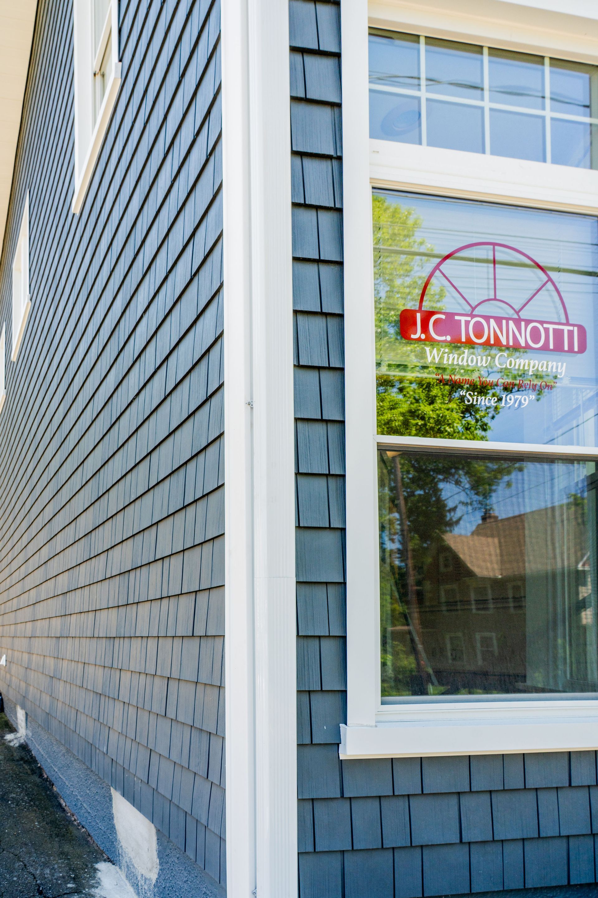 Blue-shingled building corner with white trim and window with red signage.