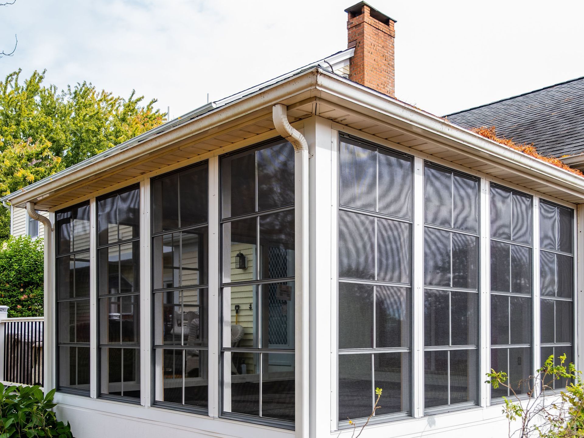 A screened in porch with a lot of windows on the side of a house.