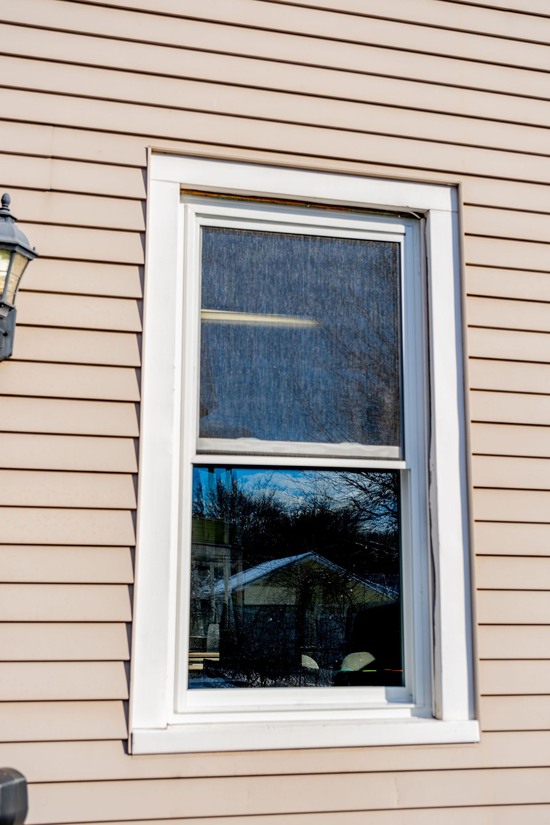 A double hung window on the side of a house with a white frame.