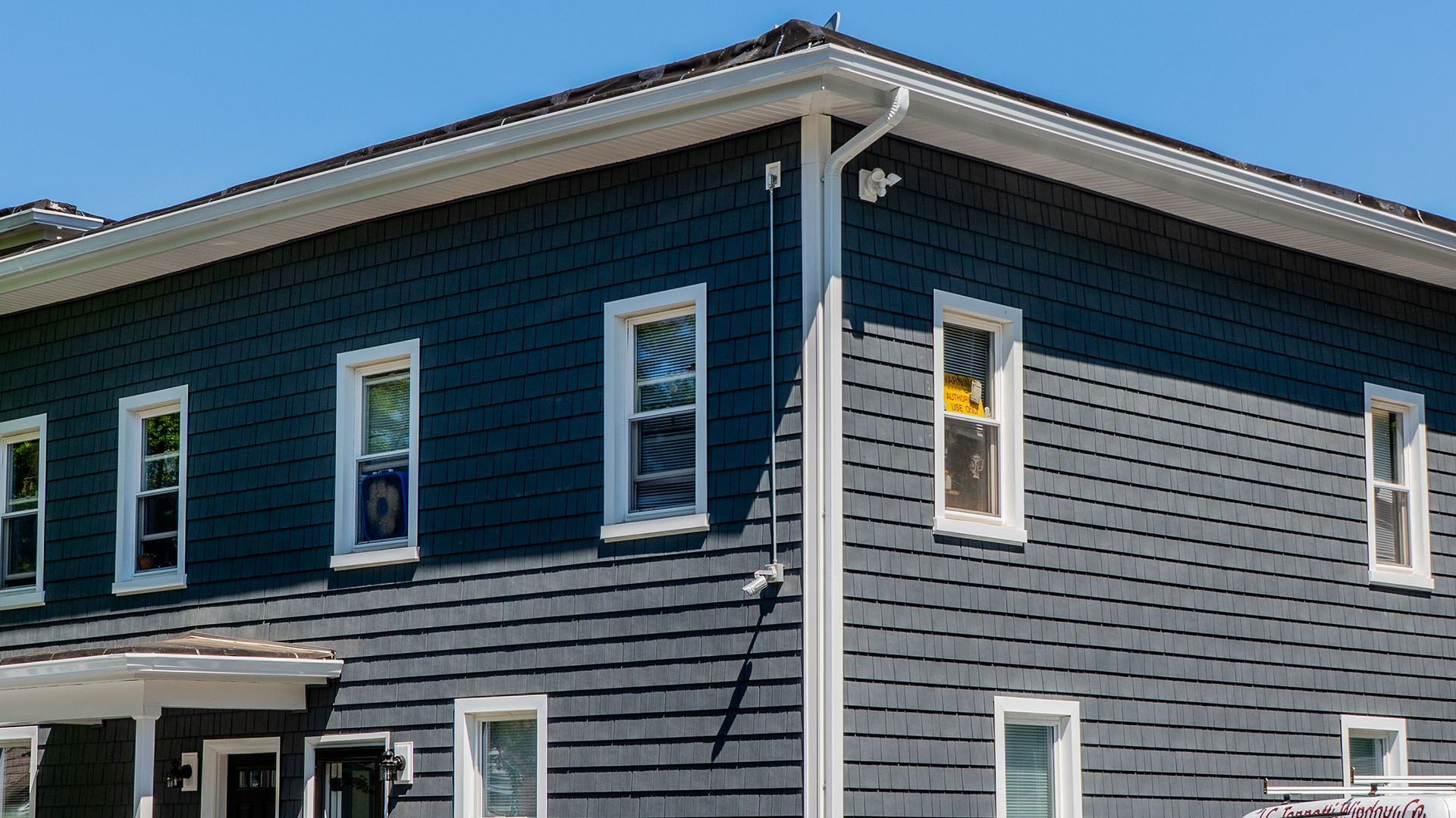 A large gray house with white trim and windows on a sunny day.