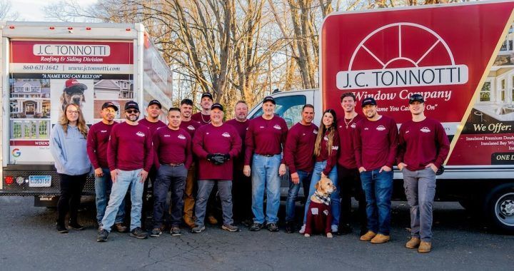 A group of people are posing for a picture in front of a truck of jc tonnotti