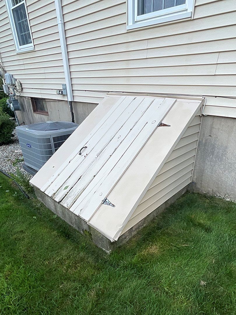 A wooden cellar door is sitting on the side of a house.